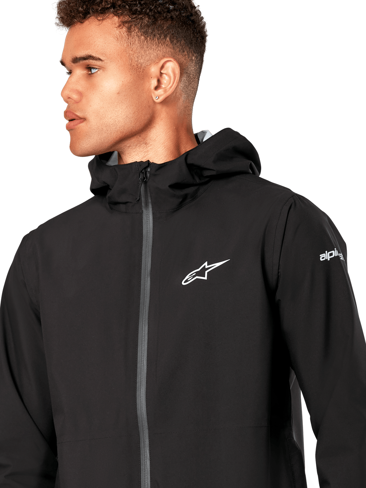 Alpinestars Kascade regnjakke, sort regnjakke, med hvidt stjernelogo på brystet, fast hætte og belagt omvendt spiralfrontlynlås, afslappet motorsportsinspireret performance-overtøj