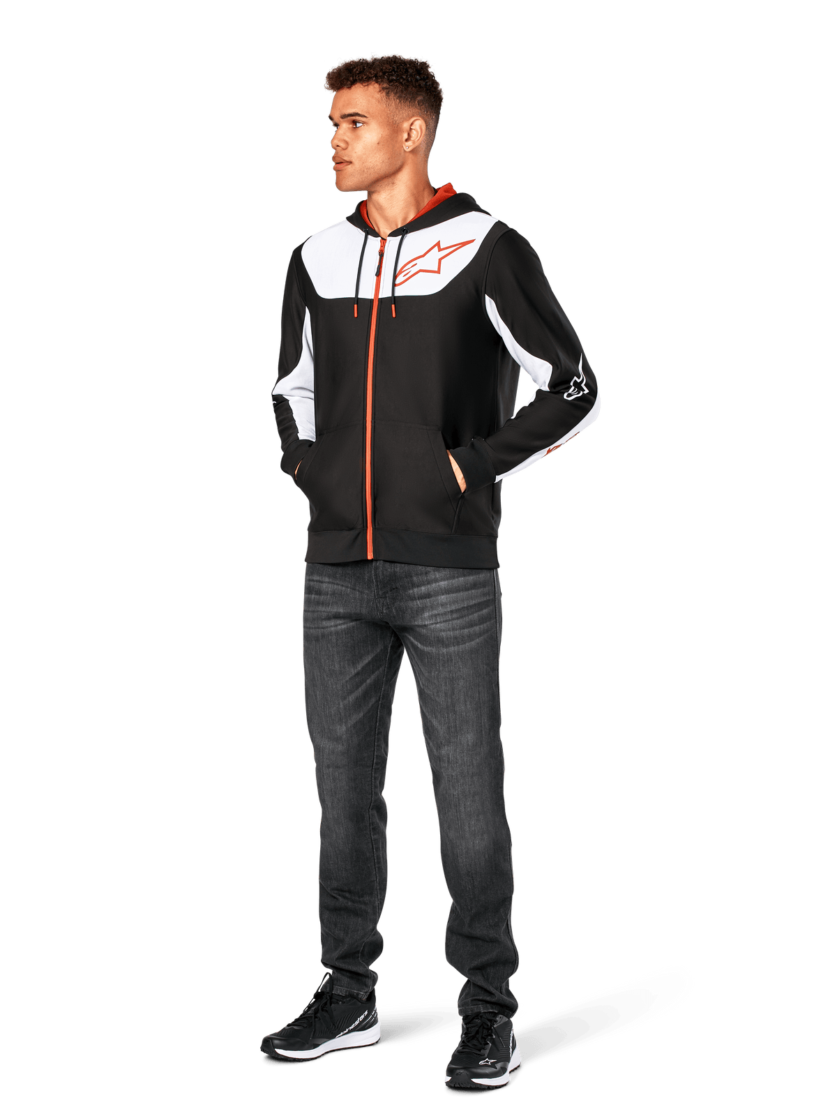 Alpinestars Sessions V3 hættetrøje, afslappet hættetrøje med lynlås foran, sort, hvid og rød, båret af model med mørke jeans og sorte sneakers, med hvide color-block-paneler på brystet og ærmerne, rød lynlås og snoredetaljer, stort brystlogo, polyfleece motorsport-inspireret streetwear