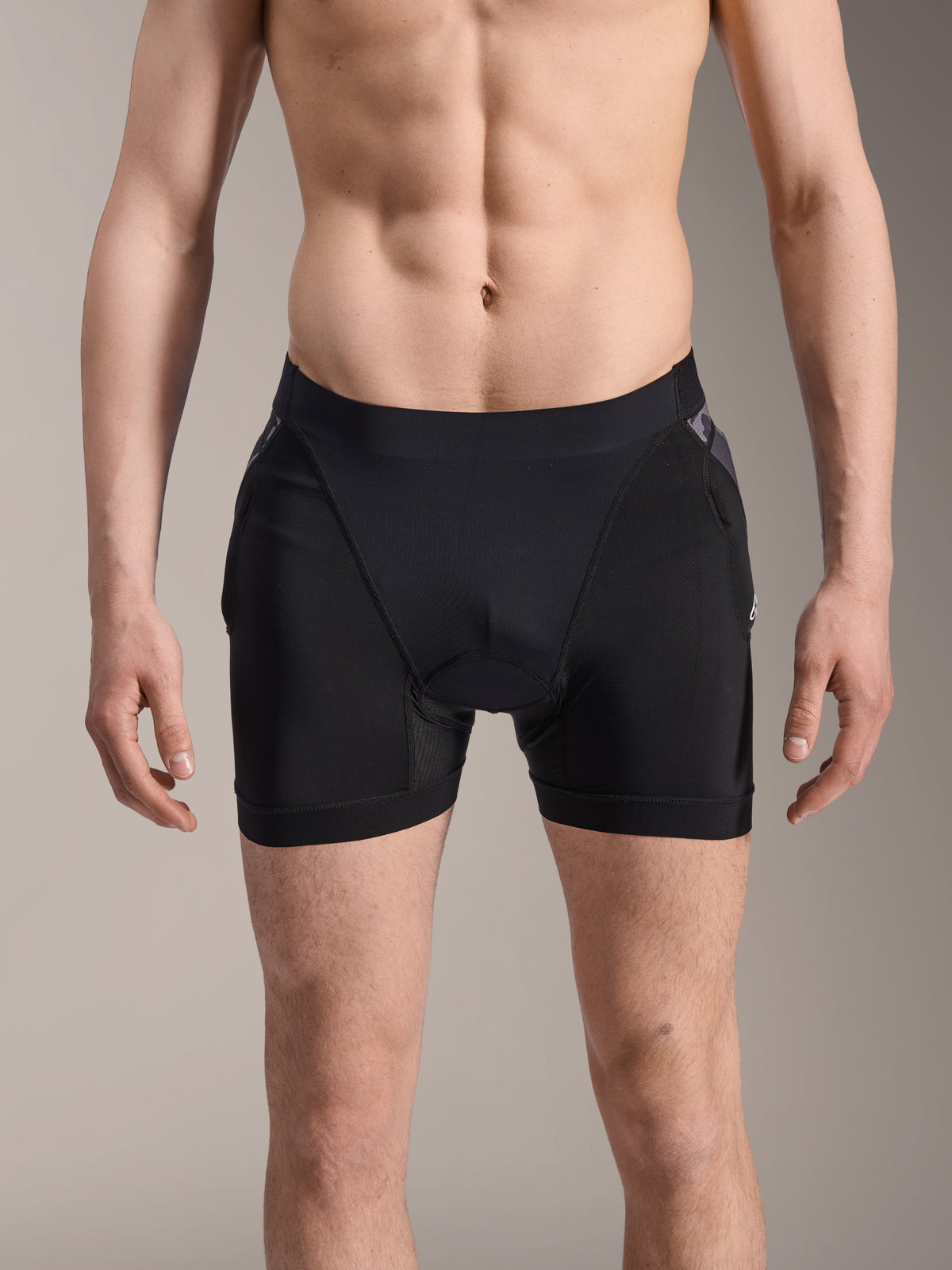 Alpinestars A-Motion Plasma beskyttelsesboxershorts, MTB-beskyttelsesshorts, sort med Black Camo-detaljer, set forfra på mandlig model, med åndbart strækmesh og integreret hoftebeskyttelse til cykling.