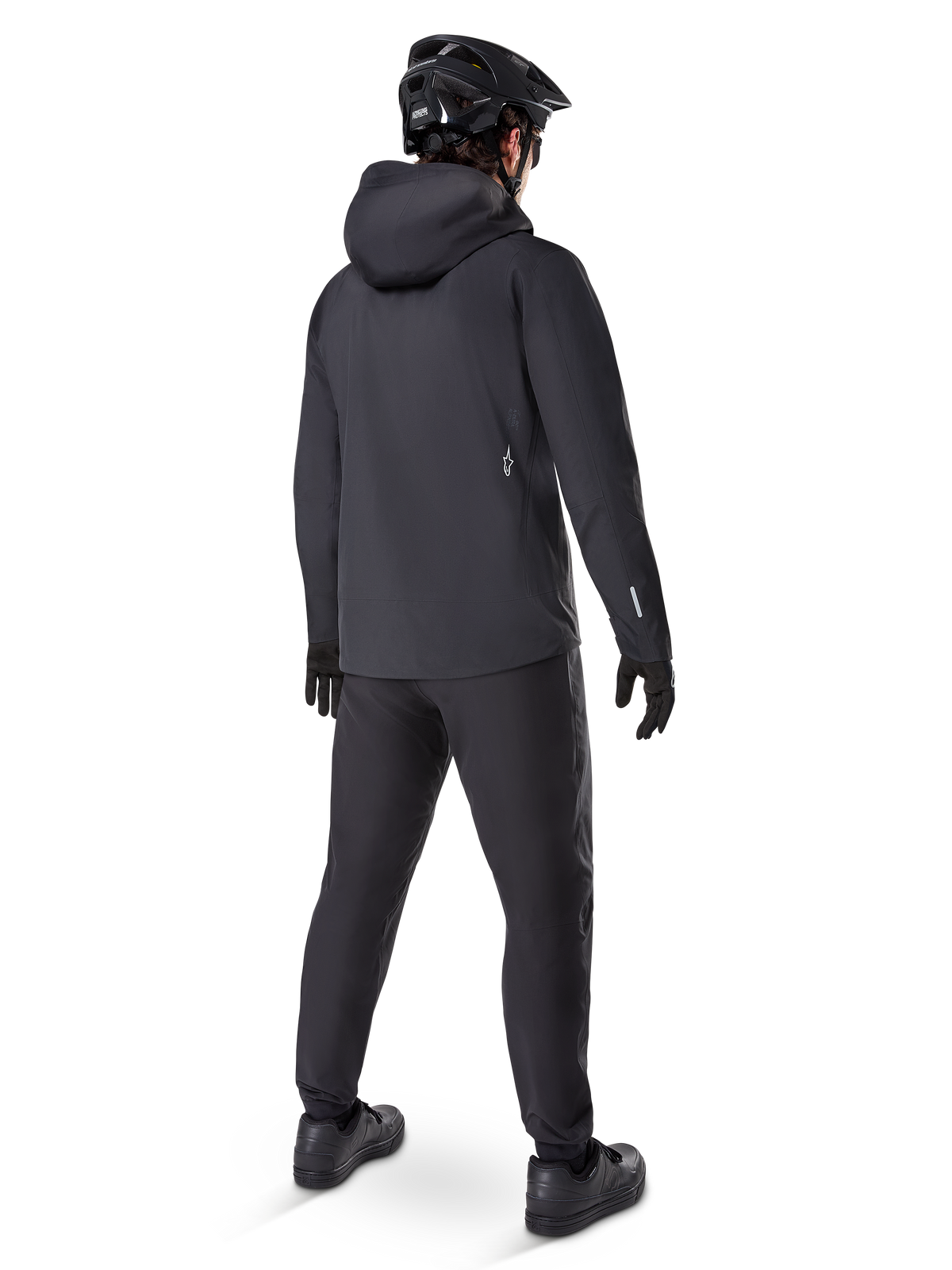 Alpinestars A-Dura Waterproof Pants, MTB-bukser, sort, set bagfra på en rytter iført et komplet sort mountainbike-outfit inklusive en jakke med hætte og hjelm, slidstærkt vandtæt udstyr til mudrede stier