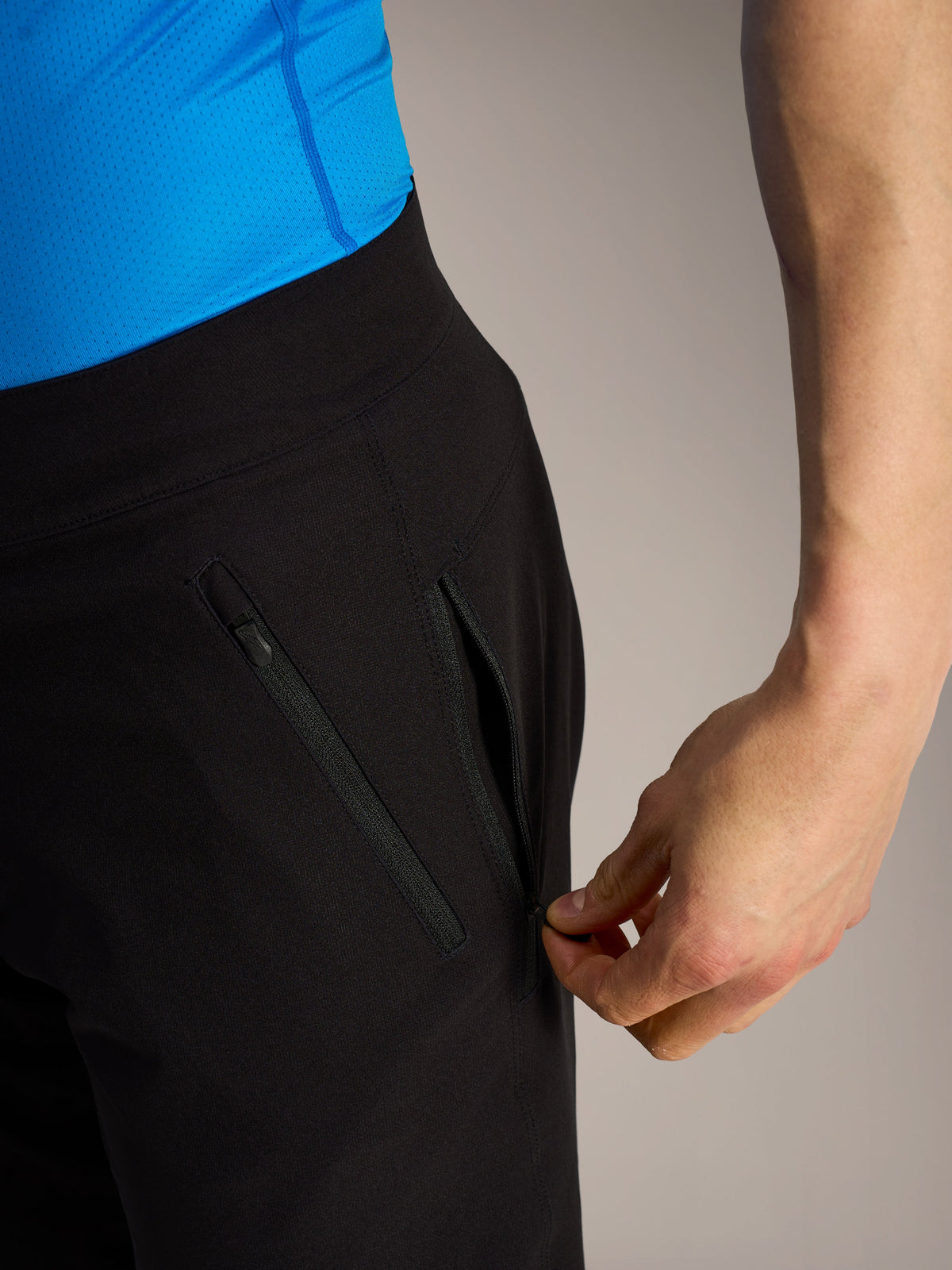 Sorte Alpinestars A-Dura Ride MTB-shorts, nærbillede af en hånd der åbner en sikker sidelomme med lynlås.