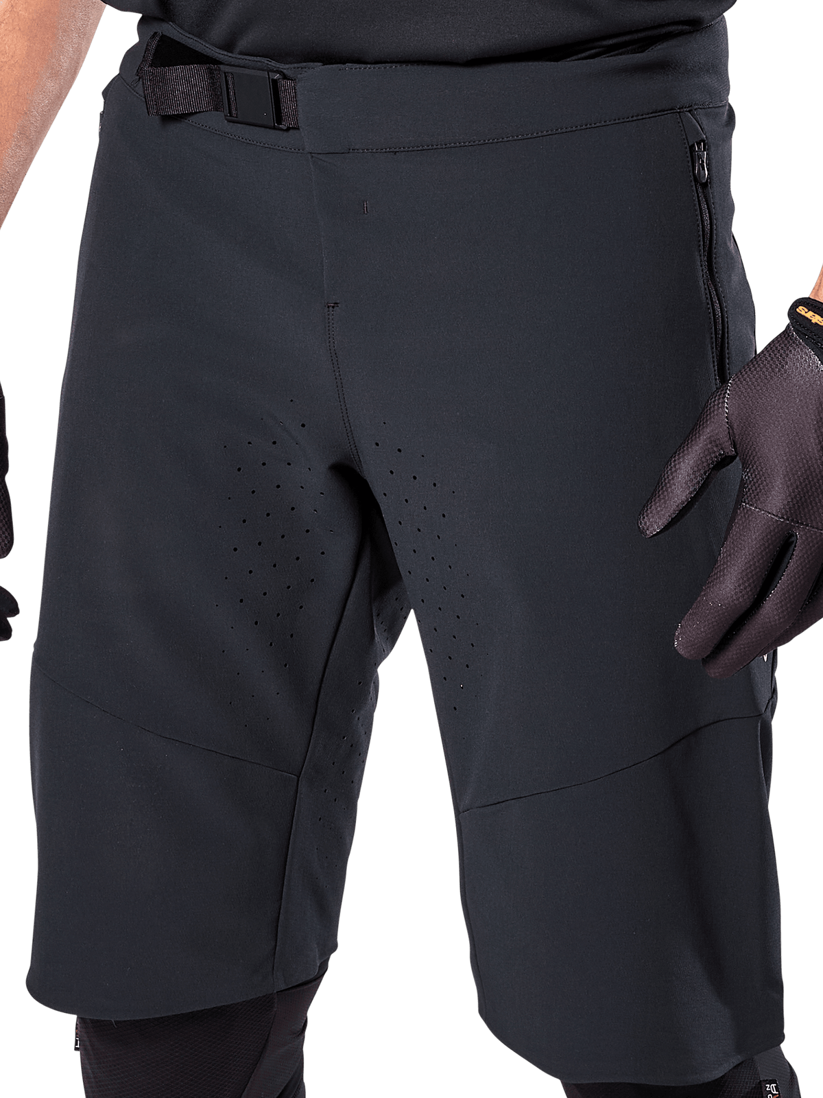 Alpinestars A-Aria Elite Shorts in Black, close-up view of the waist and thigh area, featuring magnetic buckle closure, zippered pockets, and laser-cut ventilation perforations, worn with black cycling gloves for mountain biking.