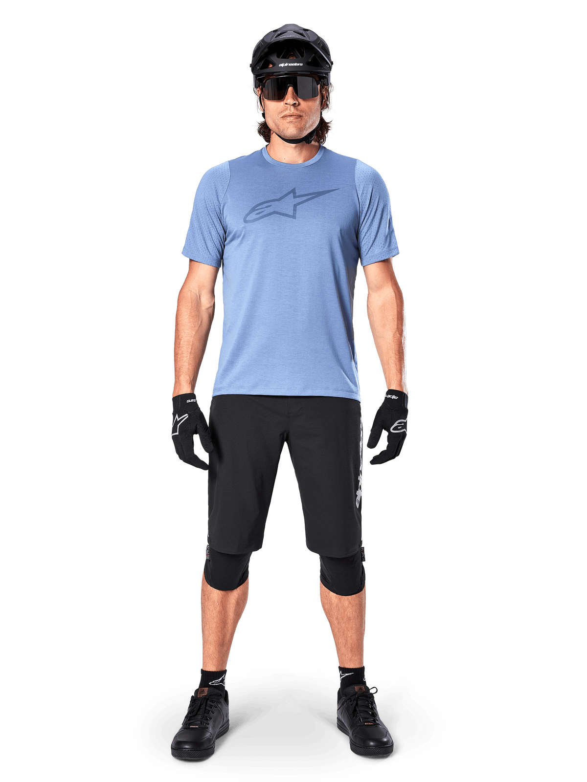 Alpinestars A-Dura Elite shorts, sorte mountainbike-shorts, båret med en lyseblå t-shirt, sort hjelm, solbriller og knæbeskyttere, professionelt cykeludstyr til terrænkørsel