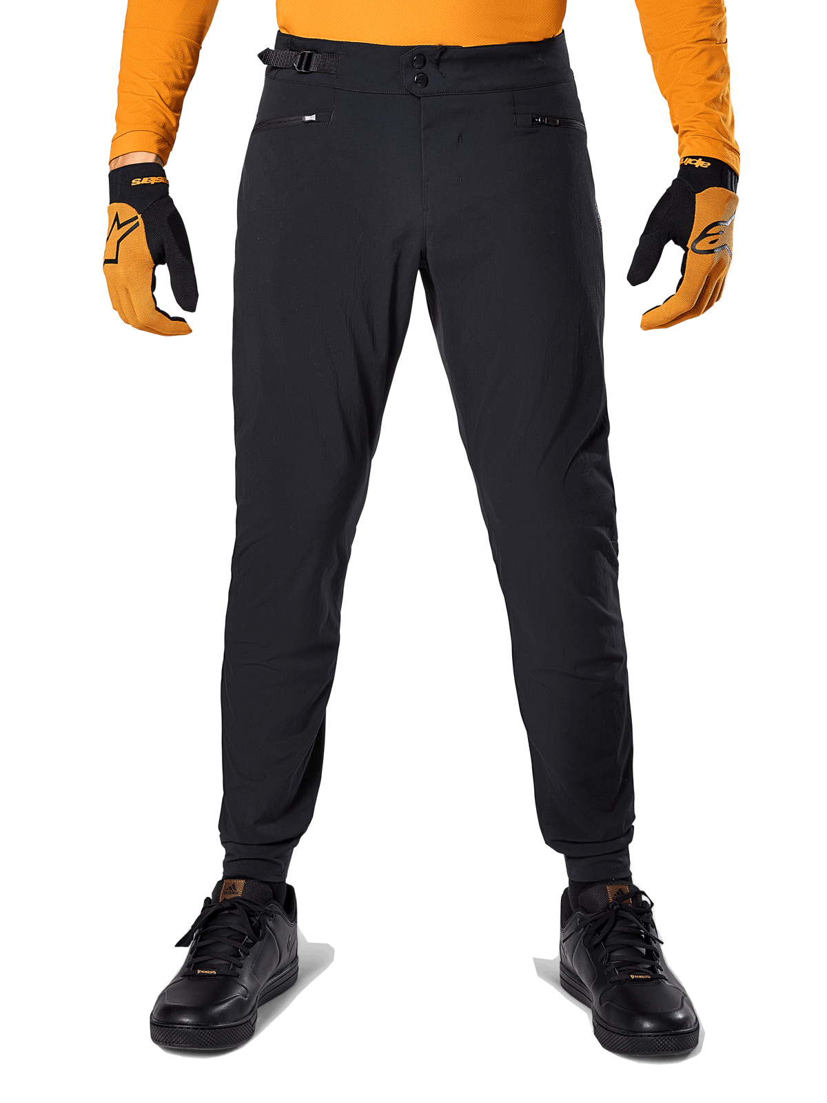 Alpinestars A-Dura Pants, Mountain Bike Pants, Black, worn with an orange long-sleeve jersey and black and orange gloves, featuring a double snap closure and side waist adjusters, durable textile for off-road cycling