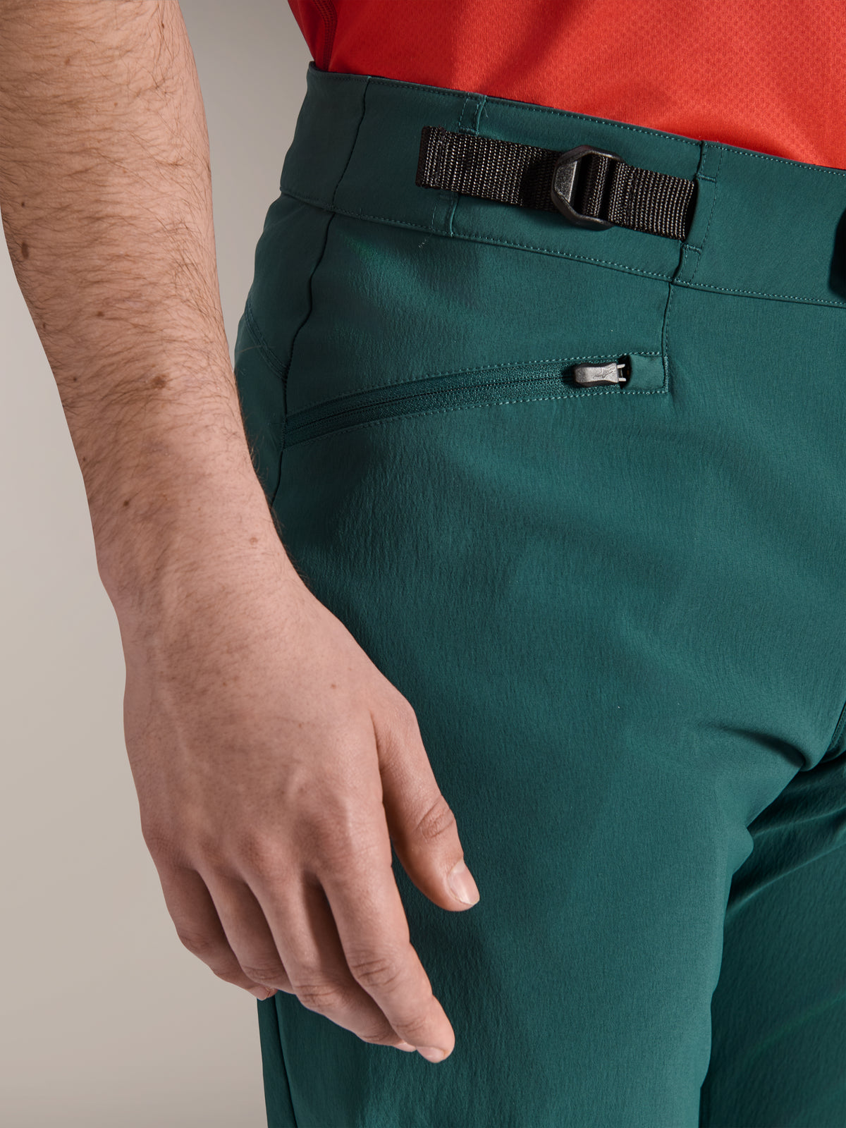 Alpinestars A-Dura bukser i Dark Pine grøn, nærbillede af den justerbare sideklemme og en lynlåslomme med mesh-for, holdbart mountainbike-tøj til off-road trail-kørsel