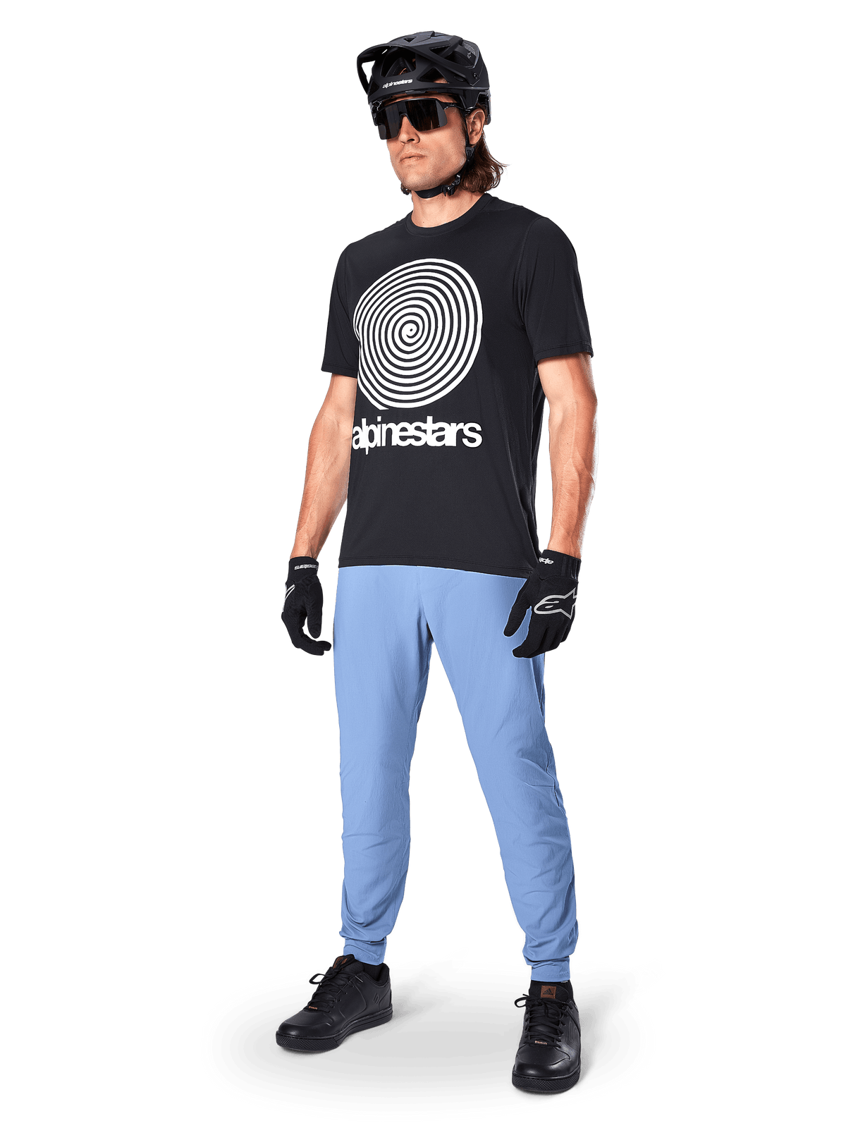 Alpinestars A-Dura Pants, MTB Pants, Infinity Blue, worn with black graphic t-shirt featuring white spiral logo, black helmet, sunglasses, and black gloves, professional mountain bike gear
