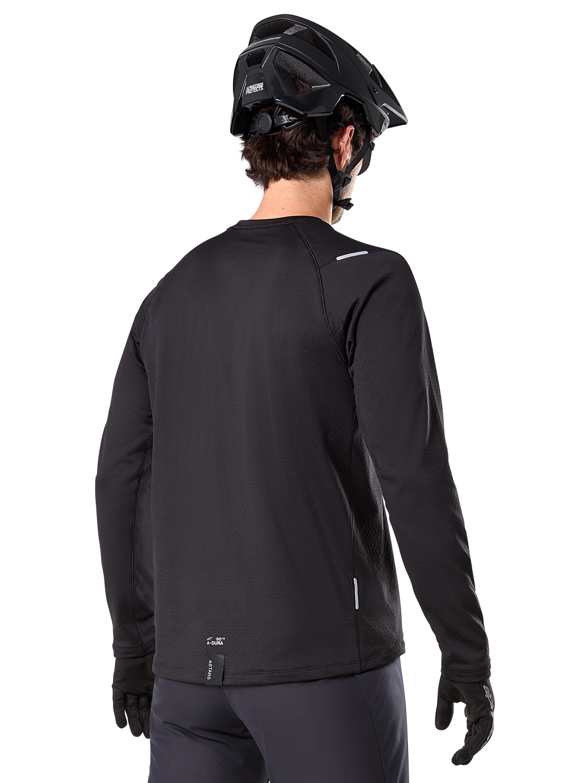 Alpinestars A-Dura Thermal Jersey, langærmet mountainbike-trøje, sort, set bagfra som viser forlænget drop tail, små refleksdetaljer og branding ved sømmen, båret med en sort hjelm og handsker til cykling i koldt vejr