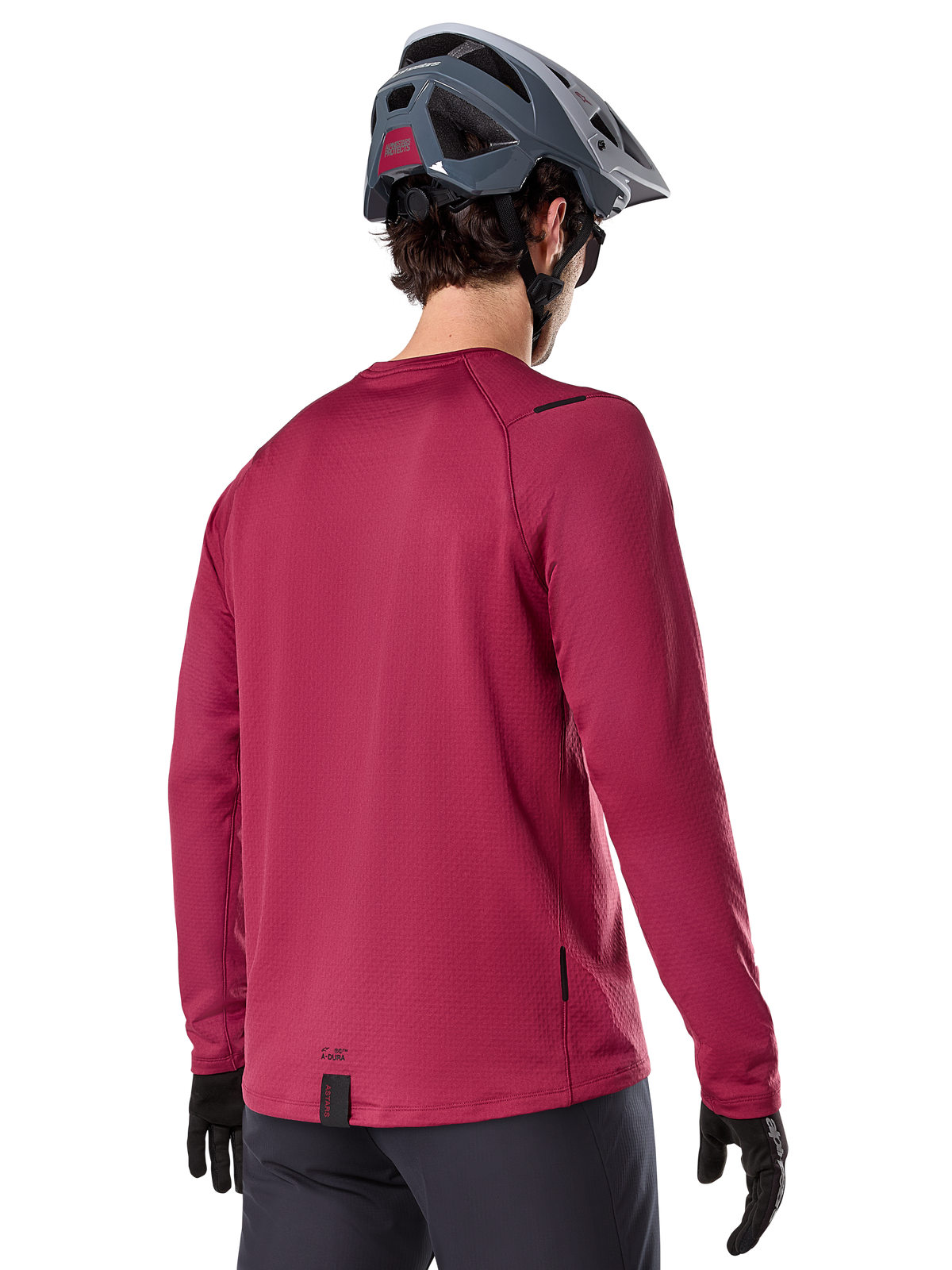 Alpinestars A-Dura Thermal trøje, langærmet mountainbike-trøje, bordeaux, set bagfra på model iført grå MTB-hjelm og sorte handsker, med forlænget rygstykke og små logodetaljer, designet til terrænkørsel i koldt vejr