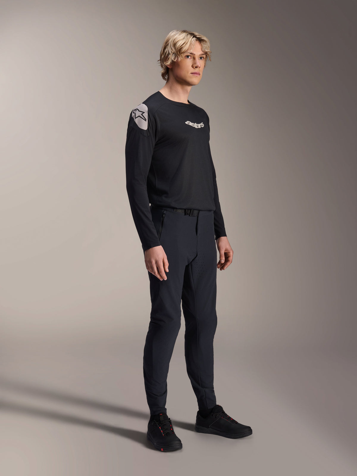 Model iført Alpinestars A-Aria Polartec Elite langærmet jersey i sort, kombineret med matchende sorte tekniske mountainbike-bukser og sorte sko, performance-cykeltøj til terrænkørsel, studiebillede