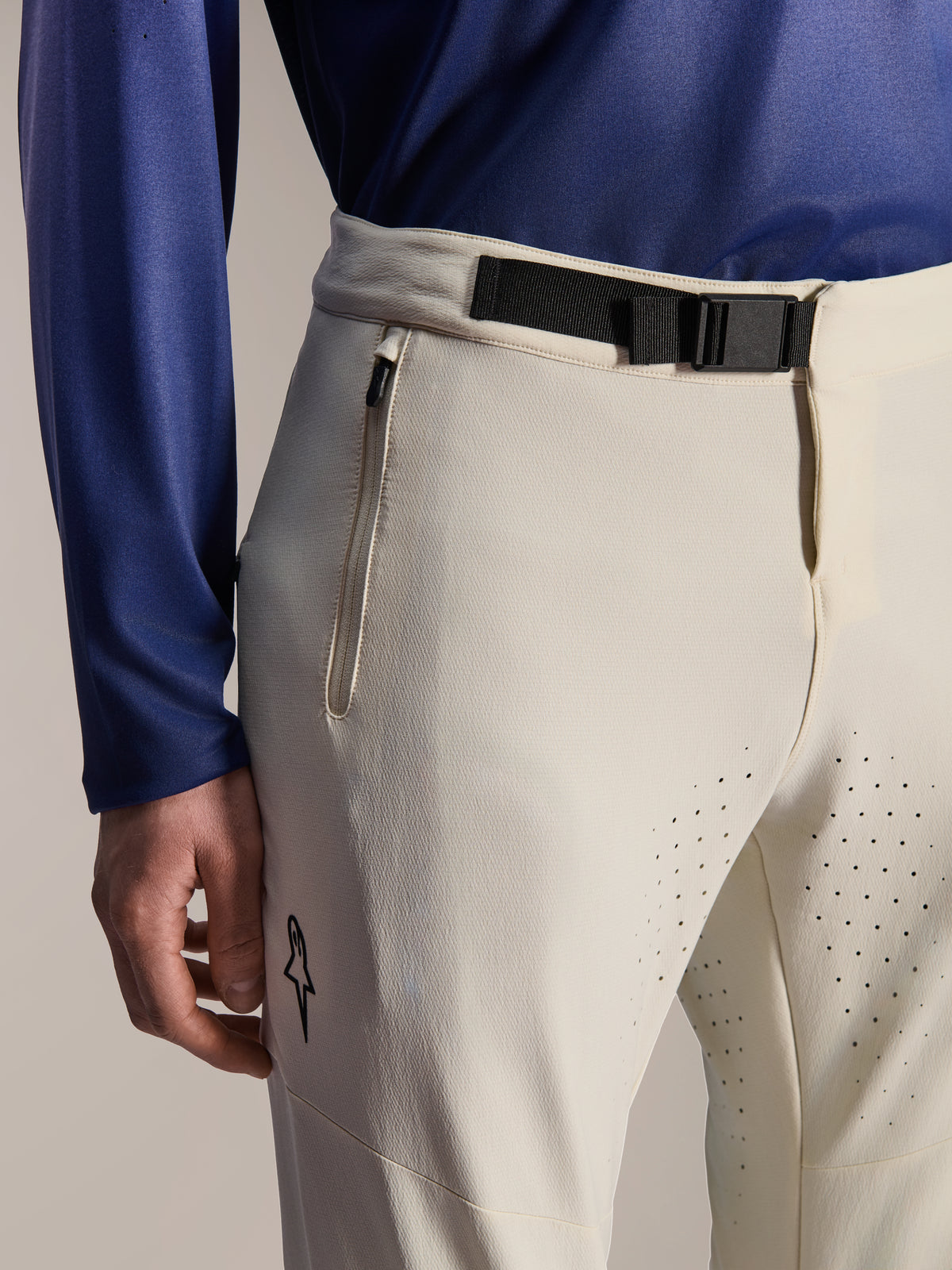 Alpinestars A-Aria Elite bukser, mountainbike-bukser, Ecru, nærbillede med en sort magnetisk spændelukning i taljen, lynlåslomme og laserskårne ventilationshuller, performance off-road cykeludstyr.
