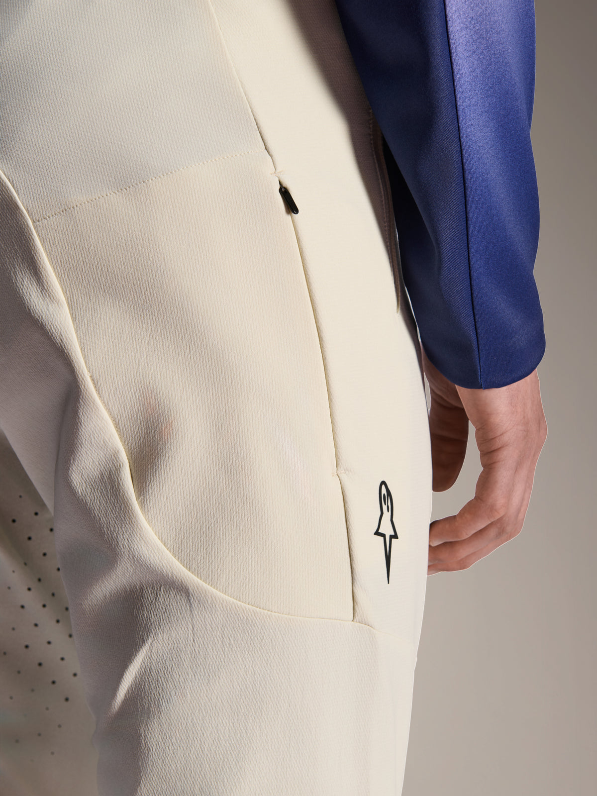 Alpinestars A-Aria Elite bukser, ecru off-white performance-bukser, nærbillede af sidelomme med lynlås og laserperforeringer til ventilation, minimalistisk logodetalje, materiale med høj strækbarhed til mountainbiking