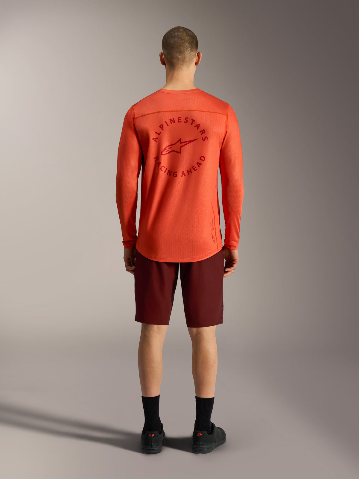 Orange A-Dura Air langærmet trøje og bordeauxrøde Ride-shorts, set bagfra af teknisk Alpinestars MTB-tøj.