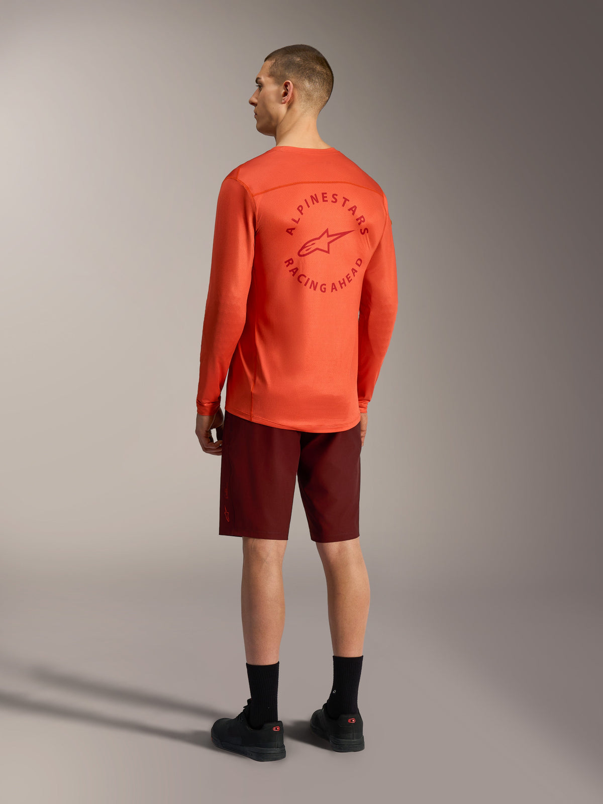 Orange A-Dura Air langærmet trøje med grafik på ryggen og bordeaux A-Dura Ride shorts, performance MTB-gear.