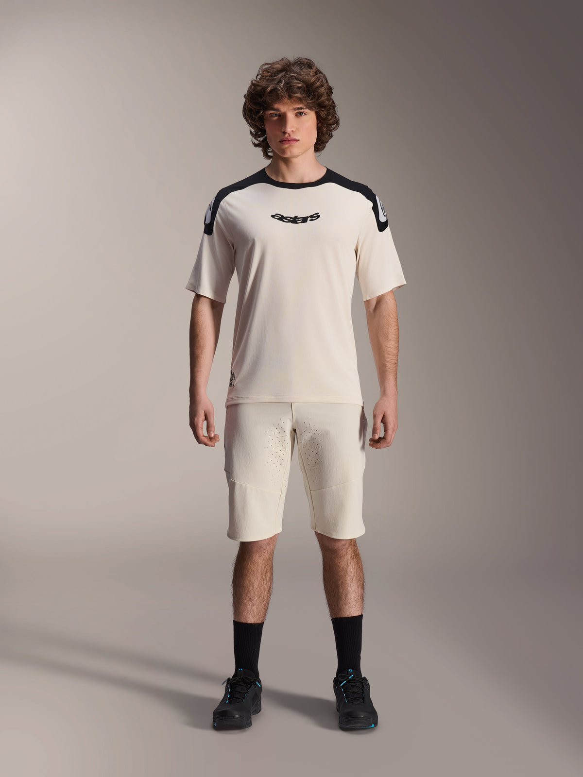 Alpinestars A-Aria Polartec Elite Short Sleeve Jersey in Ecru, featuring black shoulder panels and centered chest logo, paired with matching ecru shorts, black socks and riding shoes, premium mountain bike riding gear.