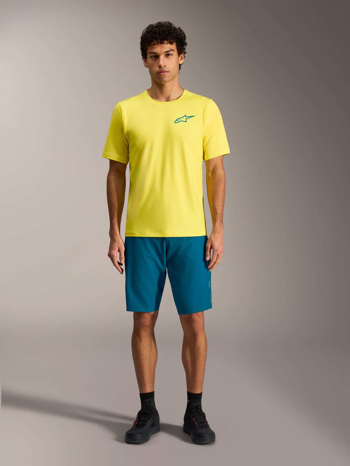 Gul Alpinestars A-Dura Air SS jersey og blågrønne A-Dura Ride shorts, MTB-outfit til mænd.