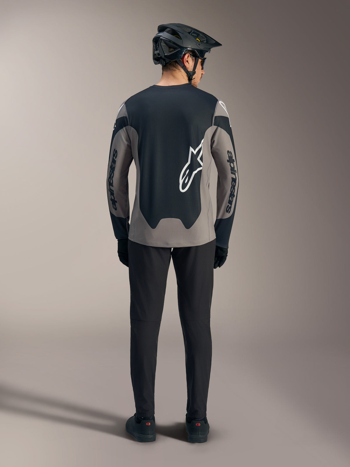 Grå Alpinestars A-Dura Race langærmet trøje med sorte paneler og hvide logoer, set bagfra til MTB-brug.