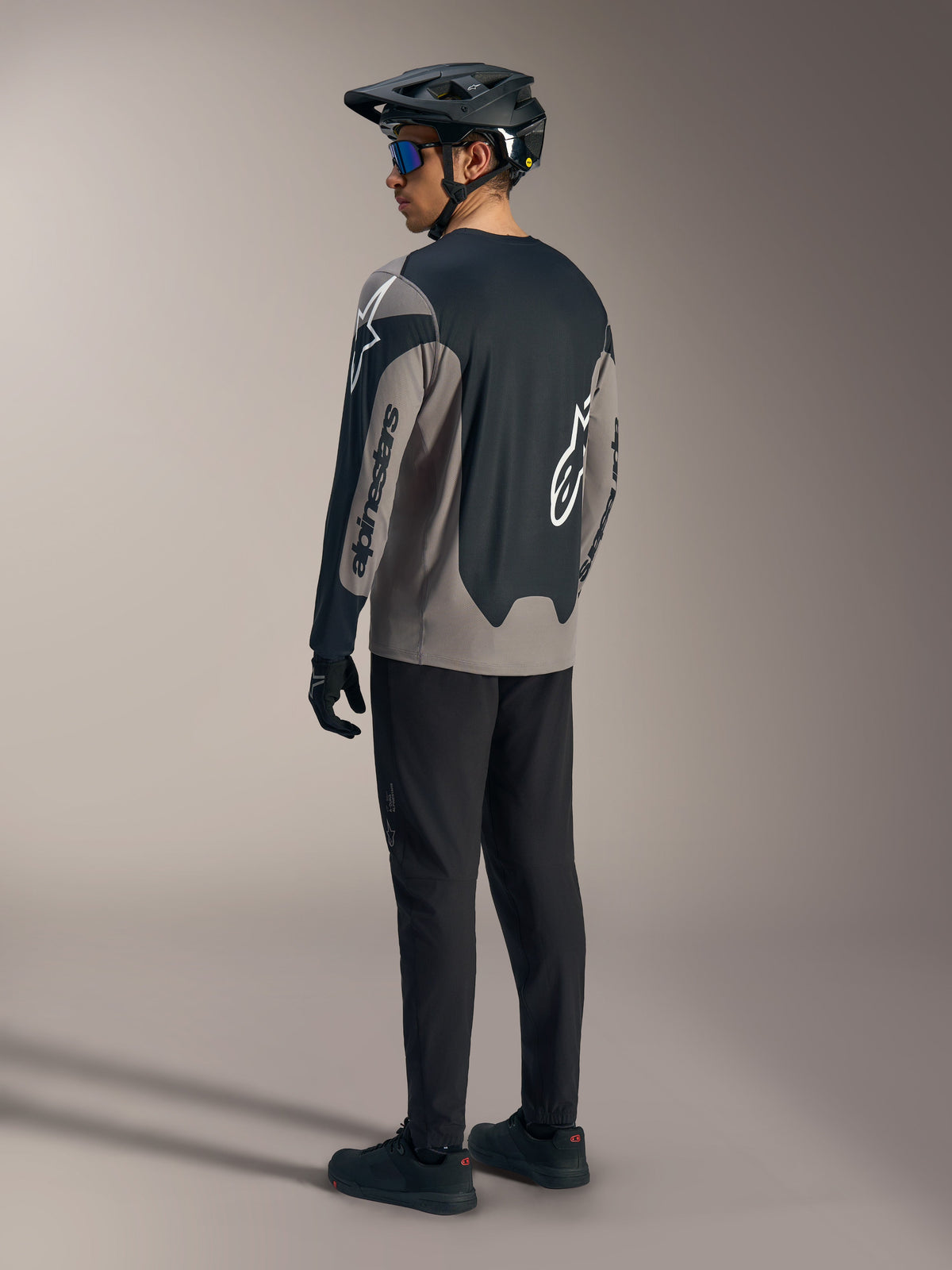 Grå og sort A-Dura Race langærmet trøje med Alpinestars-branding, vist bagfra i et komplet MTB-sæt.
