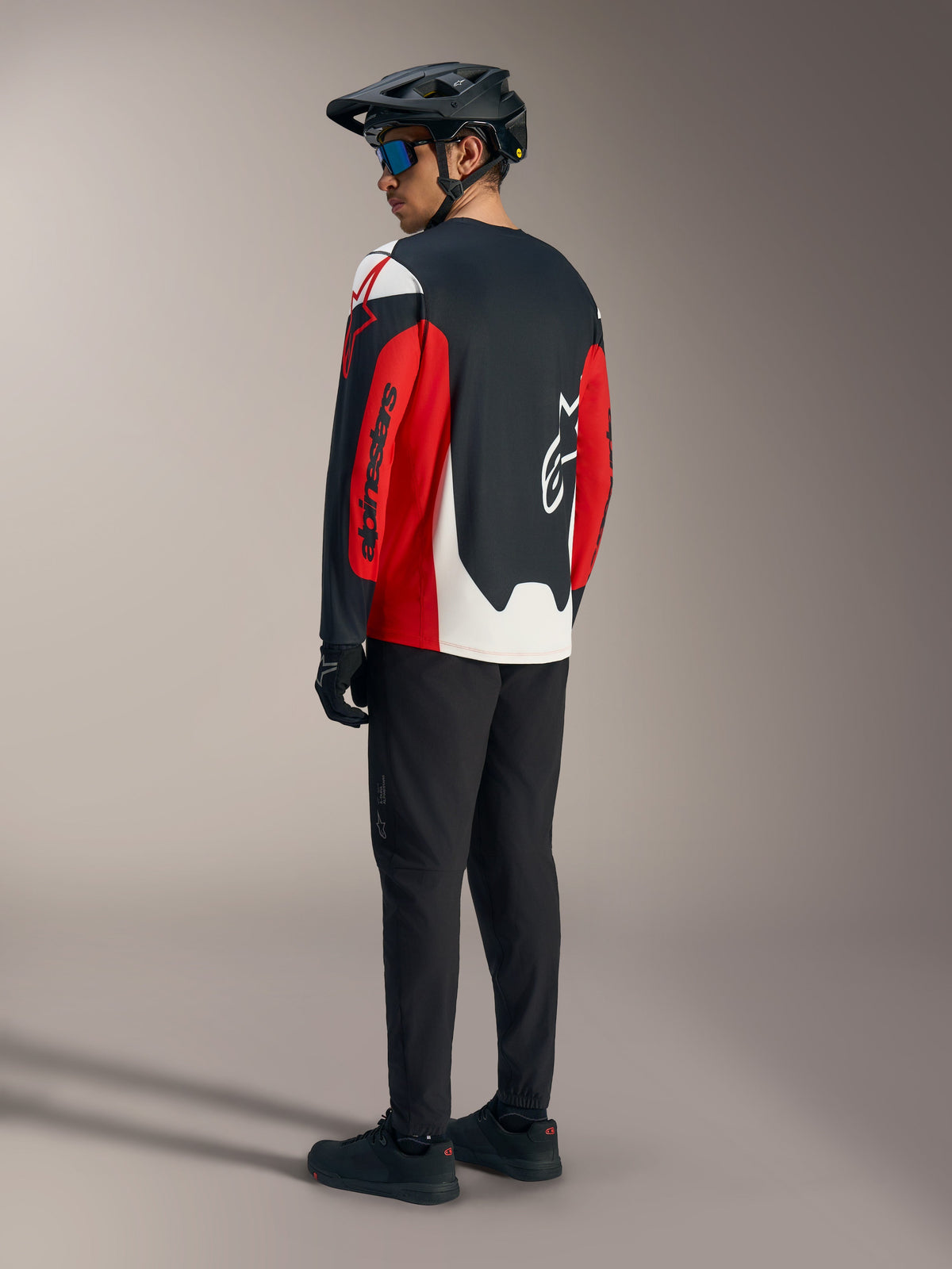 Rød A-Dura Race langærmet trøje med markant Alpinestars-grafik, set bagfra som en del af et mountainbike-sæt.
