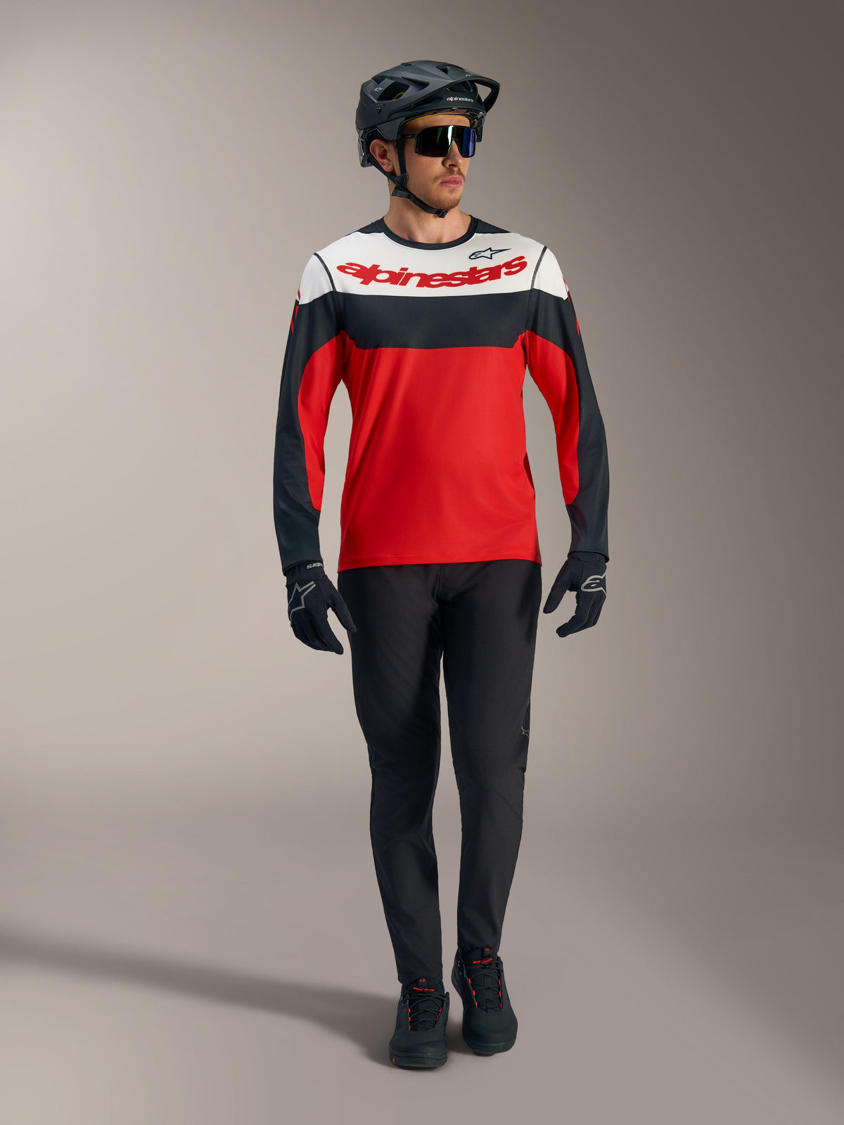 Alpinestars A-Dura Race langærmet trøje i rød med hvide og sorte paneler, parret med MTB-bukser og racingudstyr.