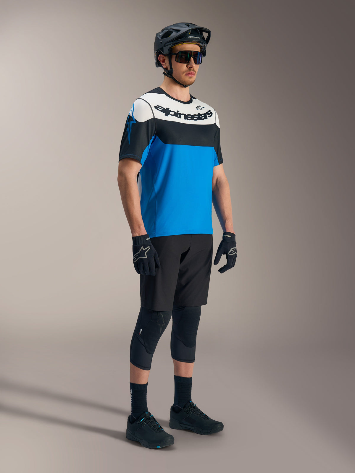 Alpinestars A-Dura Race SS jersey i blå, sort og hvid, kombineret med A-Dura Ride shorts og MTB-beskyttelsesudstyr.