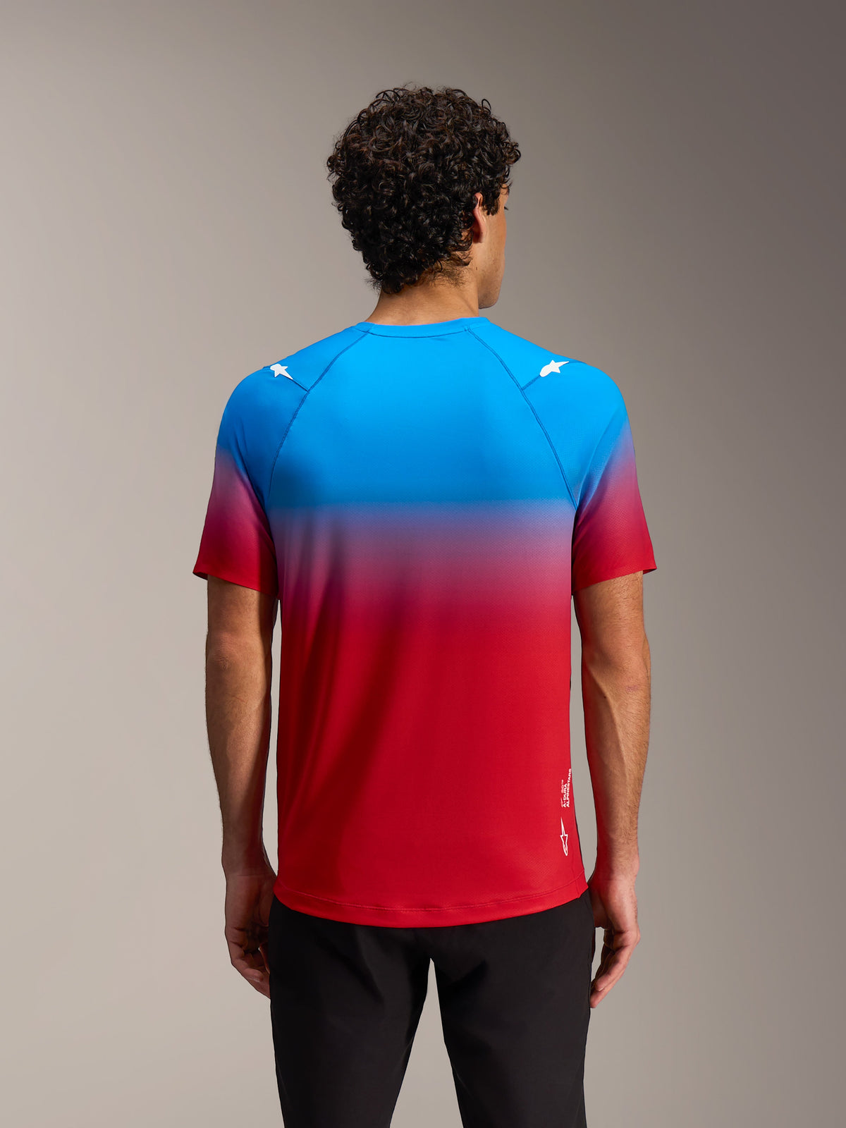 Alpinestars A-Dura ASTARS 2.0 jersey, kortærmet MTB-trøje i rød og blå gradient med stjerne-logoer, bagsidevisning.
