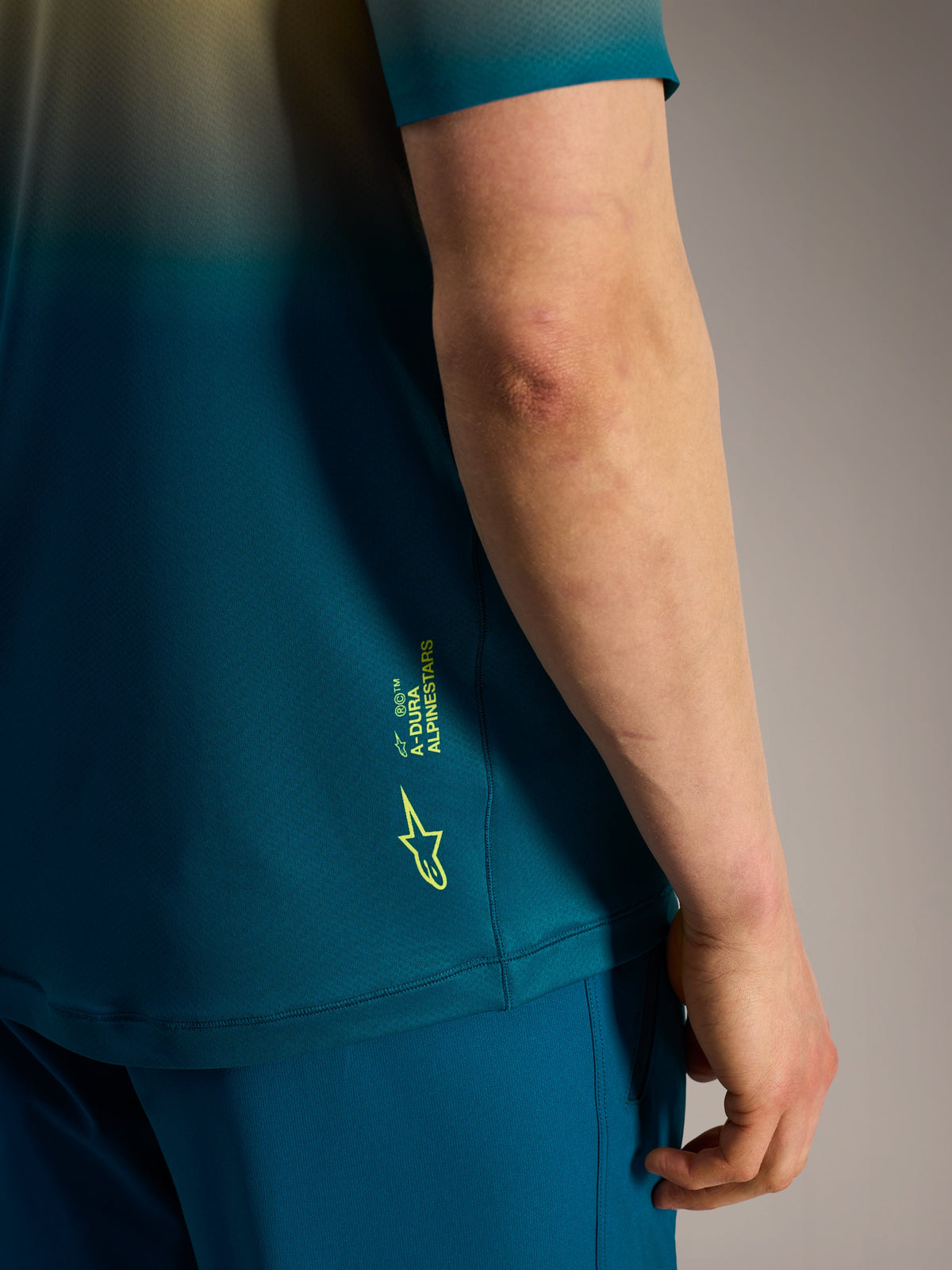 Alpinestars A-Dura ASTARS Jersey 2.0 detalje i blågrøn med neongult logo og branding på siden.