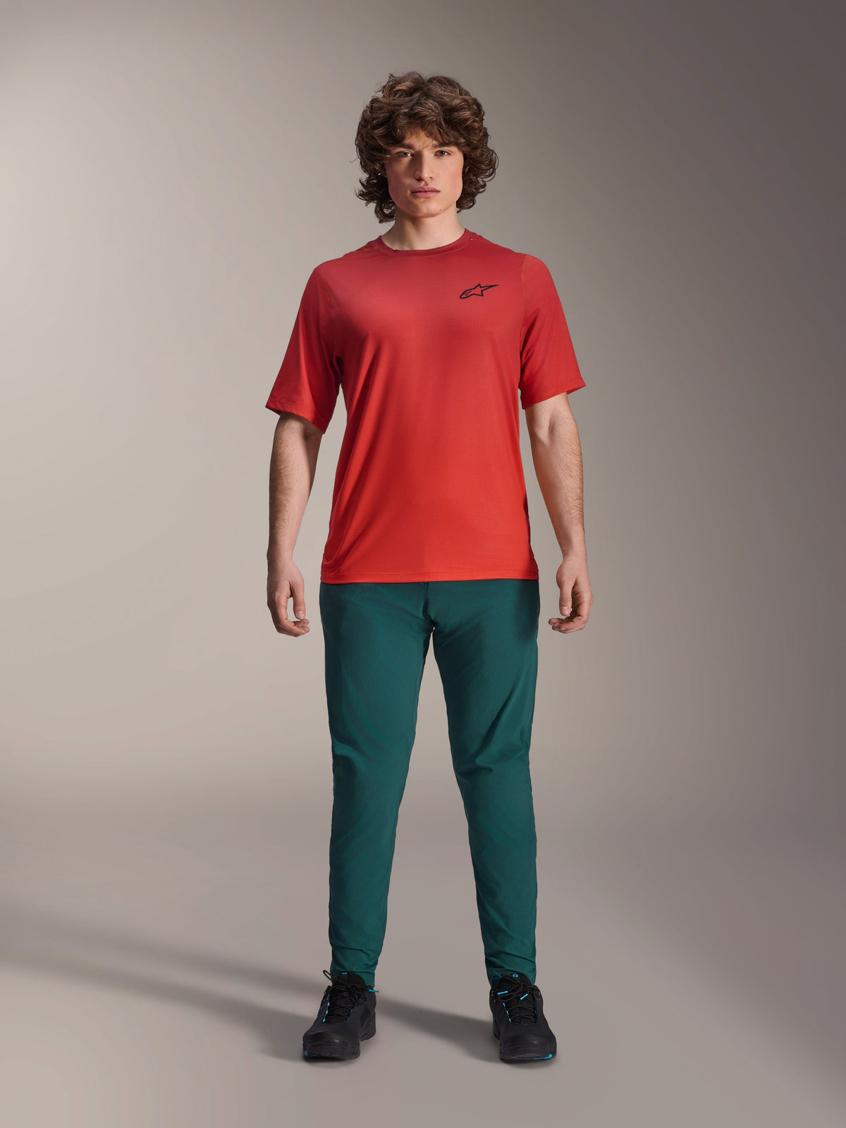 Alpinestars A-Dura Rise kortærmet jersey, Spicy Orange, båret med mørkegrønne bukser og sort fodtøj, med et sort Astars-logo på brystet, afslappet mountainbike-beklædning til off-road-kørsel