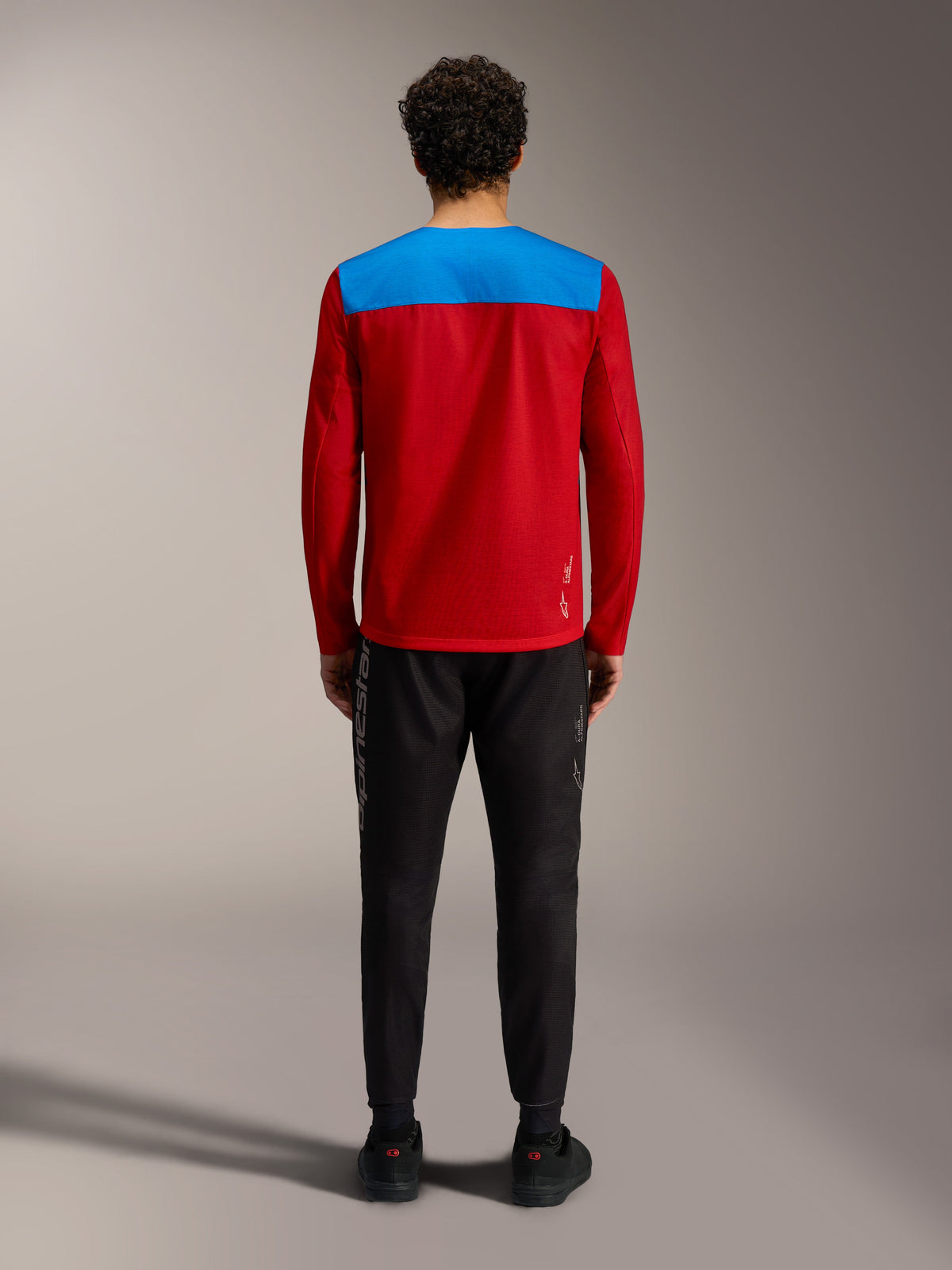 Alpinestars A-Dura Elite Trøje 2.0, rød og blå MTB-trøje set bagfra med sorte performance-bukser.