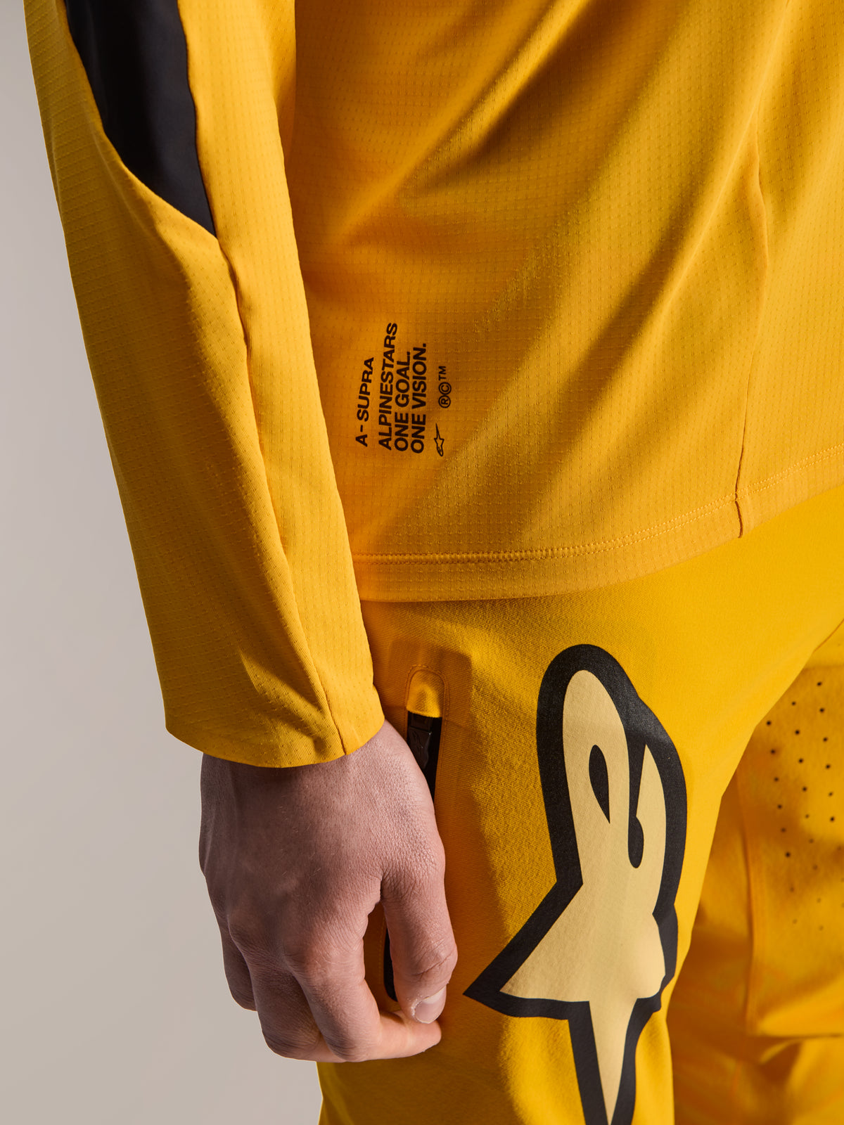 Alpinestars Limited Edition A-Supra Melt Gold bukser og matchende langærmet trøje, mørkegul, nærbillede med 'One Goal. One Vision.' branding og stort stiliseret logo på låret, højtydende MTB-udstyr