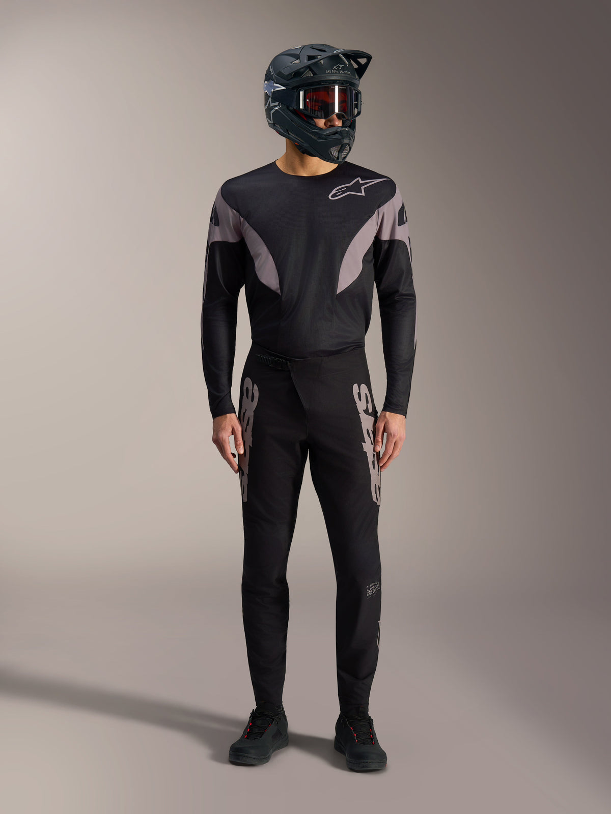Sort Alpinestars A-Supra Elite MTB-sæt med langærmet trøje, racerbukser med grå logoer og full-face hjelm.