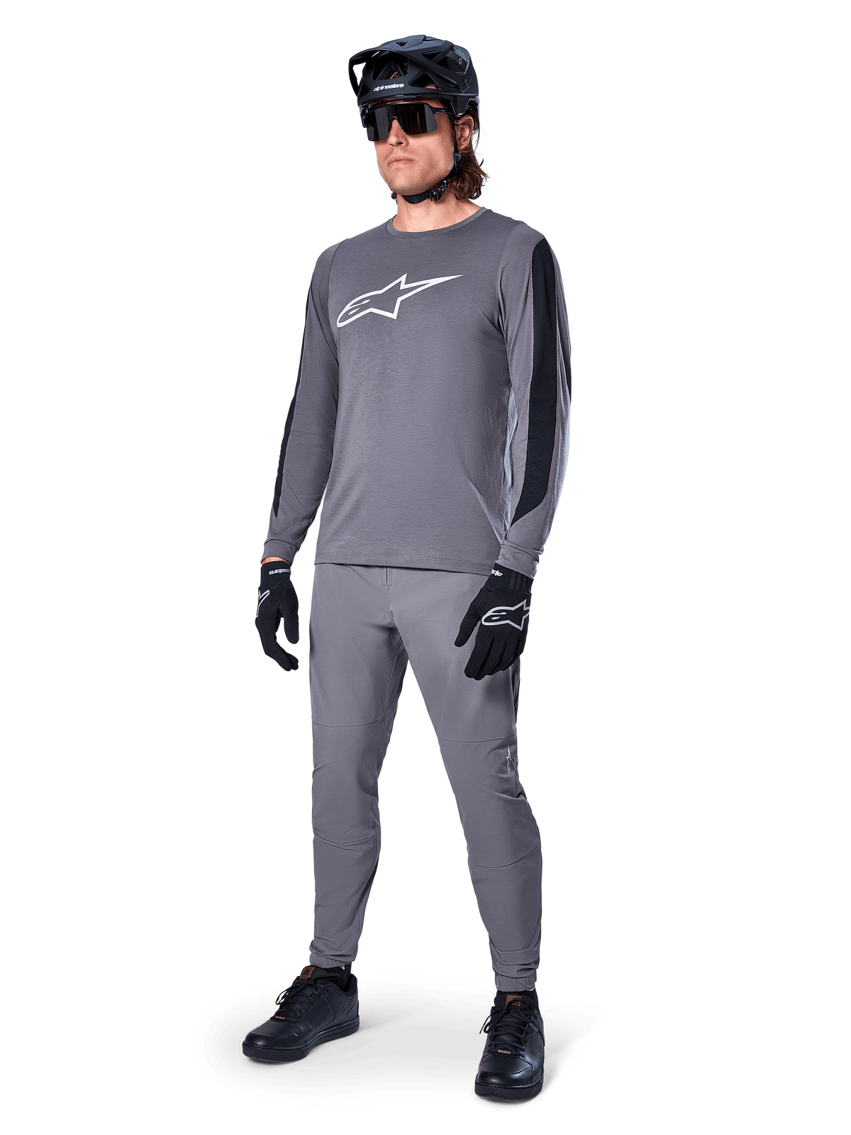 Alpinestars A-Dura Dri Astar Jersey, langærmet MTB-trøje, mørkegrå med hvidt brystlogo, sorte mesh-paneler på ærmerne, båret med matchende grå bukser, sort hjelm og handsker, performance mountainbike-tøj