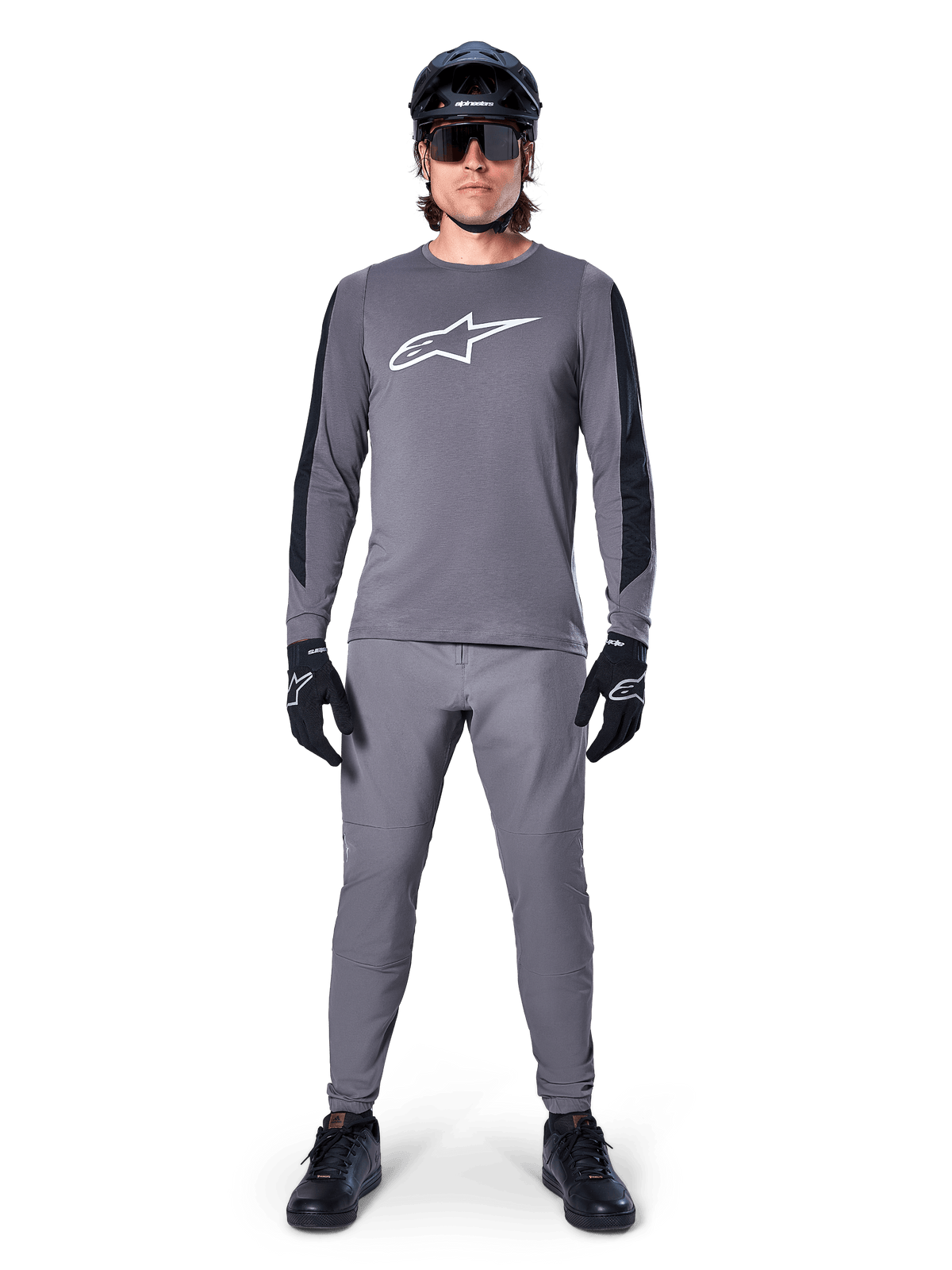 Alpinestars A-Dura Dri Astar Jersey, langærmet MTB-trøje i mørkegrå, med hvidt brystlogo og sorte ærmepaneler, her vist med matchende grå bukser, sort hjelm, solbriller og handsker som et komplet off-road cykeloutfit
