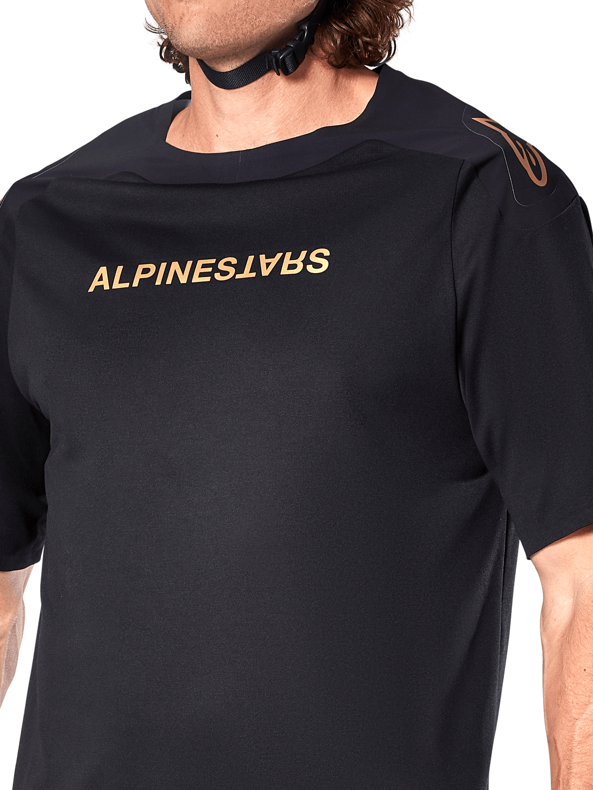 Alpinestars A-Aria Polartec Switch trøje, kortærmet MTB-trøje, sort, guld Alpinestars-skrift på brystet og logo på skulderen, nærbillede af overkroppen, der fremhæver teknisk stof og performance-pasform