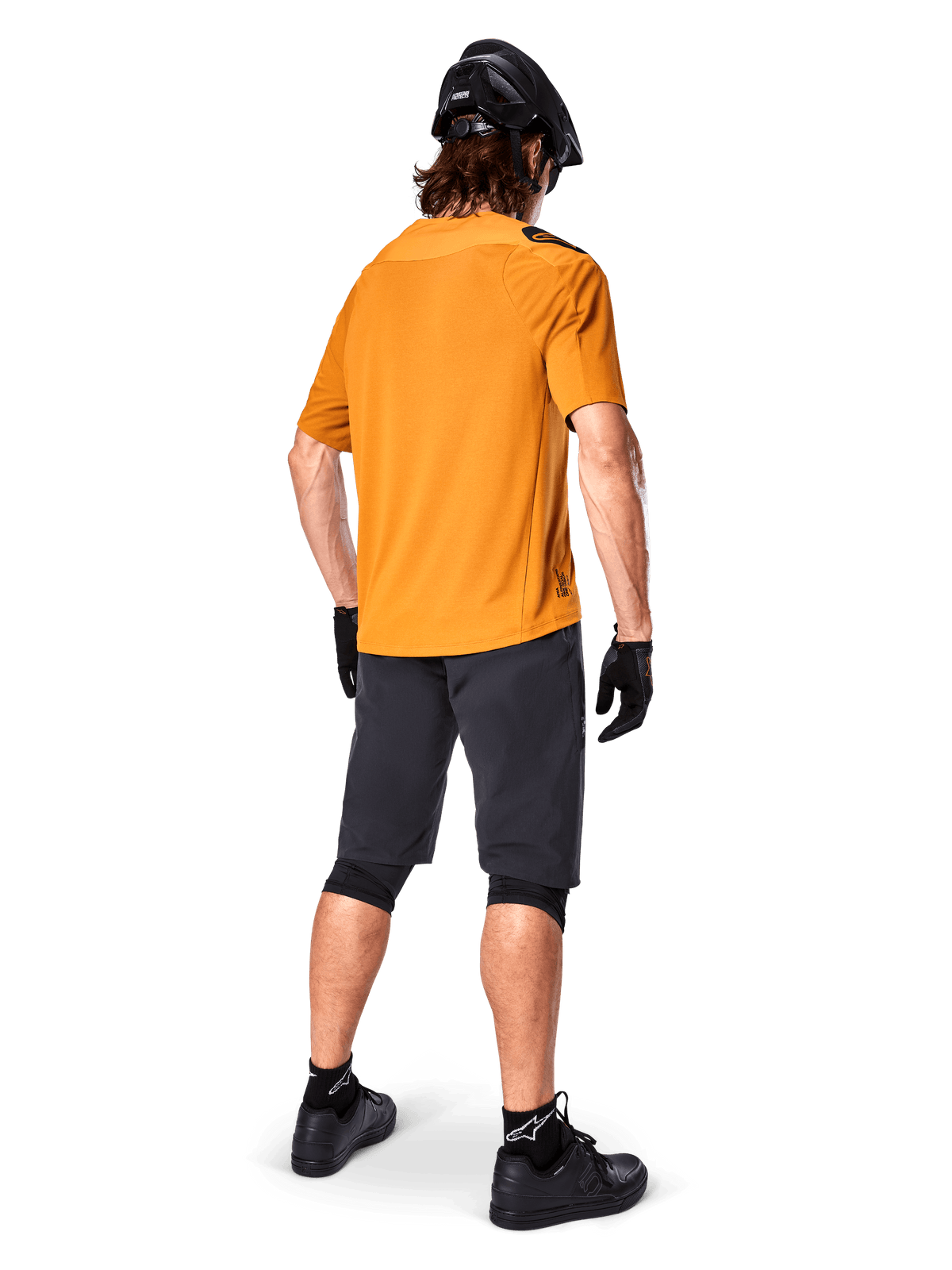 Alpinestars A-Aria Polartec Switch Jersey, Short Sleeve MTB Jersey, Dark Gold, rear view of model wearing dark gray mountain bike shorts, black helmet, and gloves, technical cycling apparel for off-road trails
