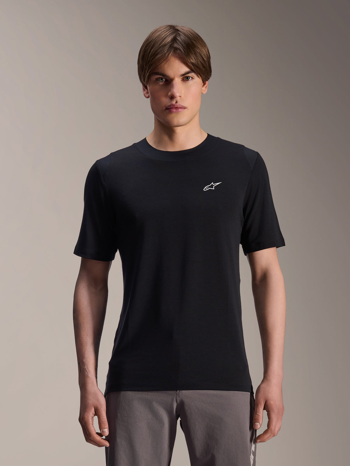 Alpinestars A-Dura Dri Wool kortærmet jersey, sort, båret af mandlig model, lille hvidt Alpinestars-logo på brystet, teknisk cykeltøj til MTB trail-kørsel, svedtransporterende drirelease-uldstof