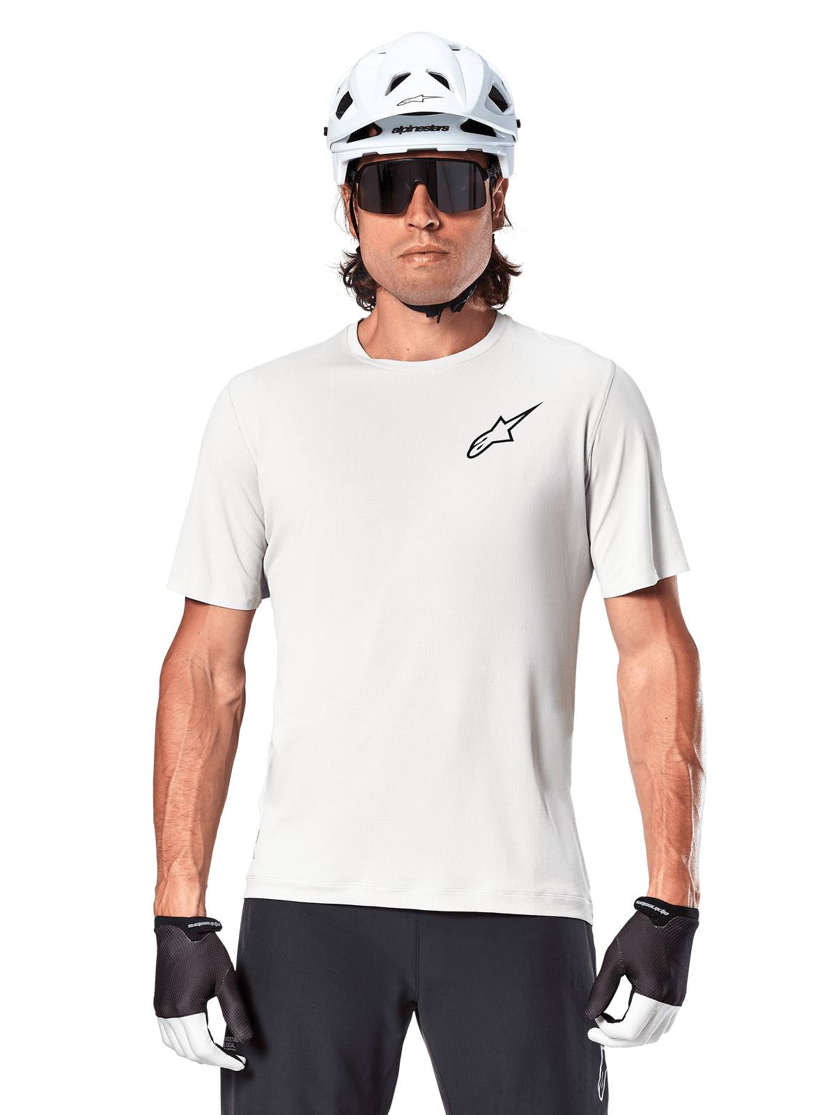 Cyclist wearing Alpinestars A-Aria Astar Short Sleeve Jersey, White Dove with small black Astar logo on chest, white cycling helmet, black sunglasses, and black and white gloves, performance MTB gear for off-road riding