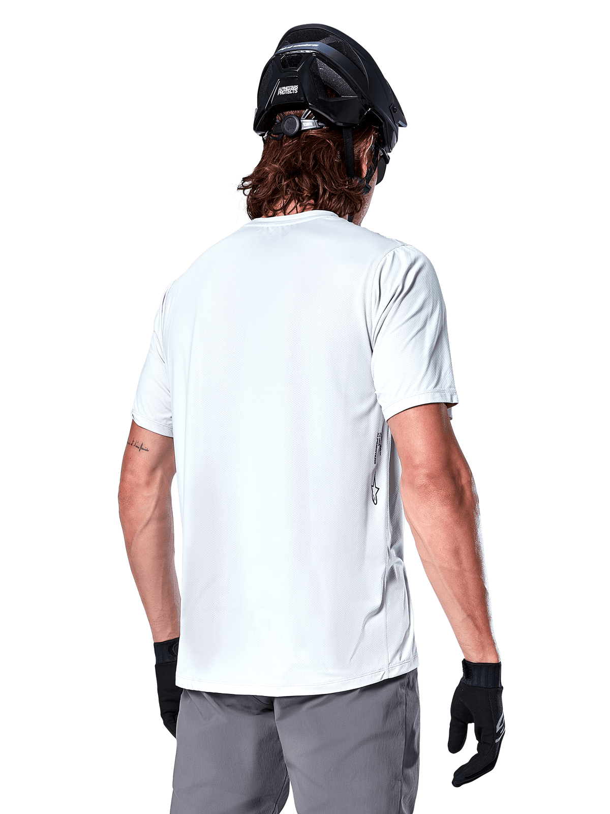 Alpinestars A-Dura Oscar jersey, kortærmet MTB-jersey, White Dove, set bagfra på en rytter iført en sort cykelhjelm, grå shorts og sorte handsker, teknisk high-performance cykeludstyr