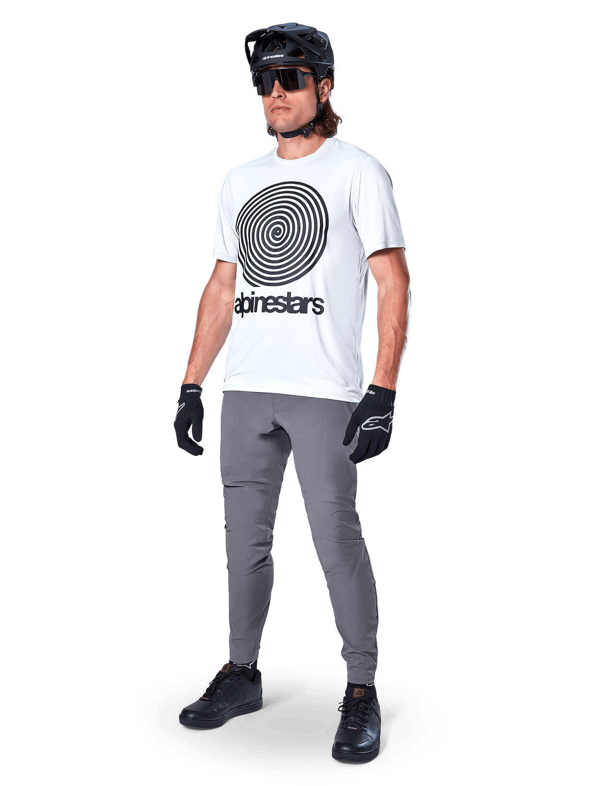 Alpinestars A-Dura Oscar kortærmet jersey, White Dove med stor sort spiralgrafik, båret af en rytter med grå MTB-bukser, sort hjelm og handsker, performance-cykeltøj til terrænkørsel
