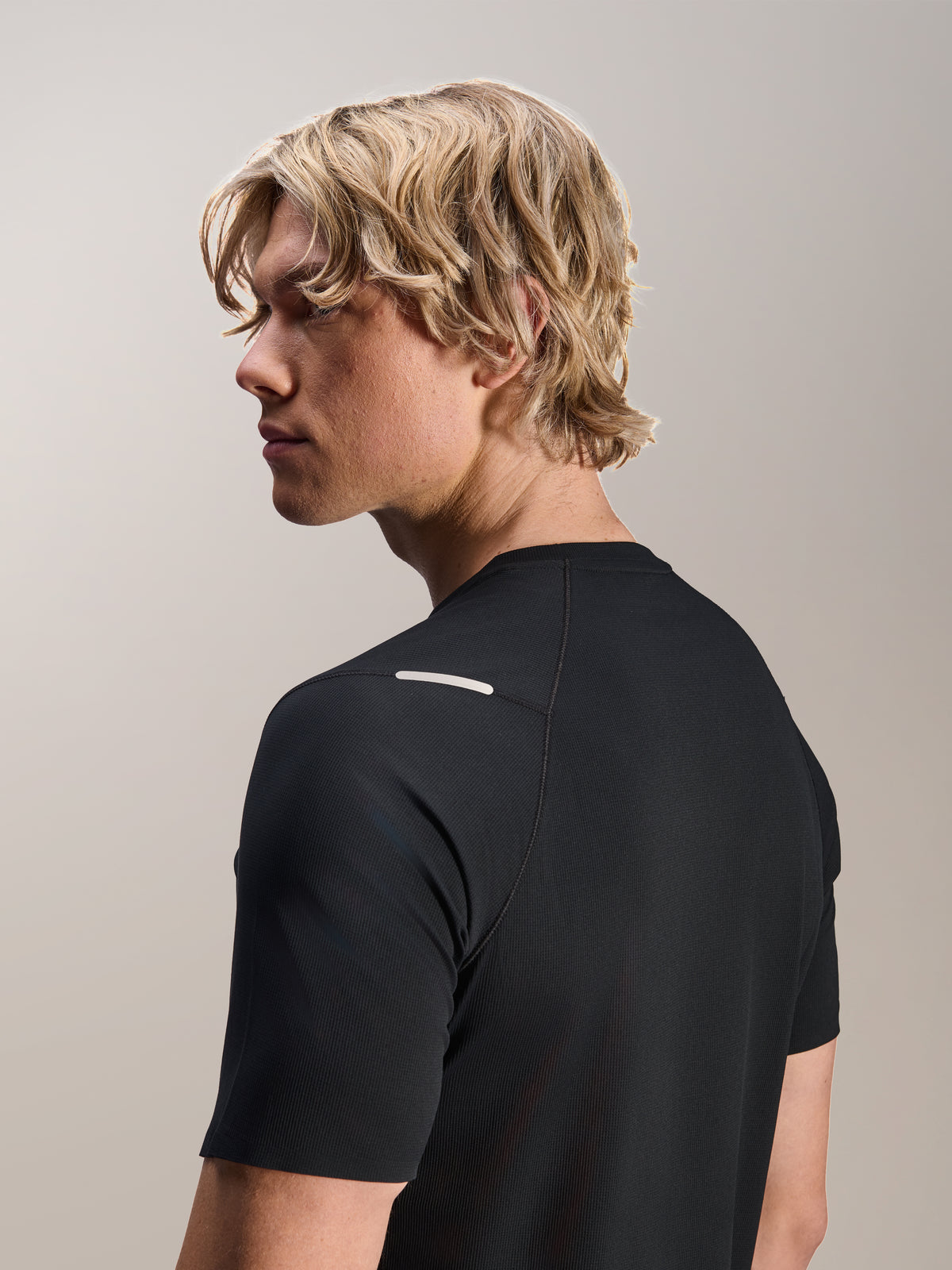 Mand iført Alpinestars A-Aria Switch Jersey, kortærmet, sort, set fra siden og bagfra, der viser performance-fit og skulderdetaljer, letvægts åndbart MTB-cykeltøj