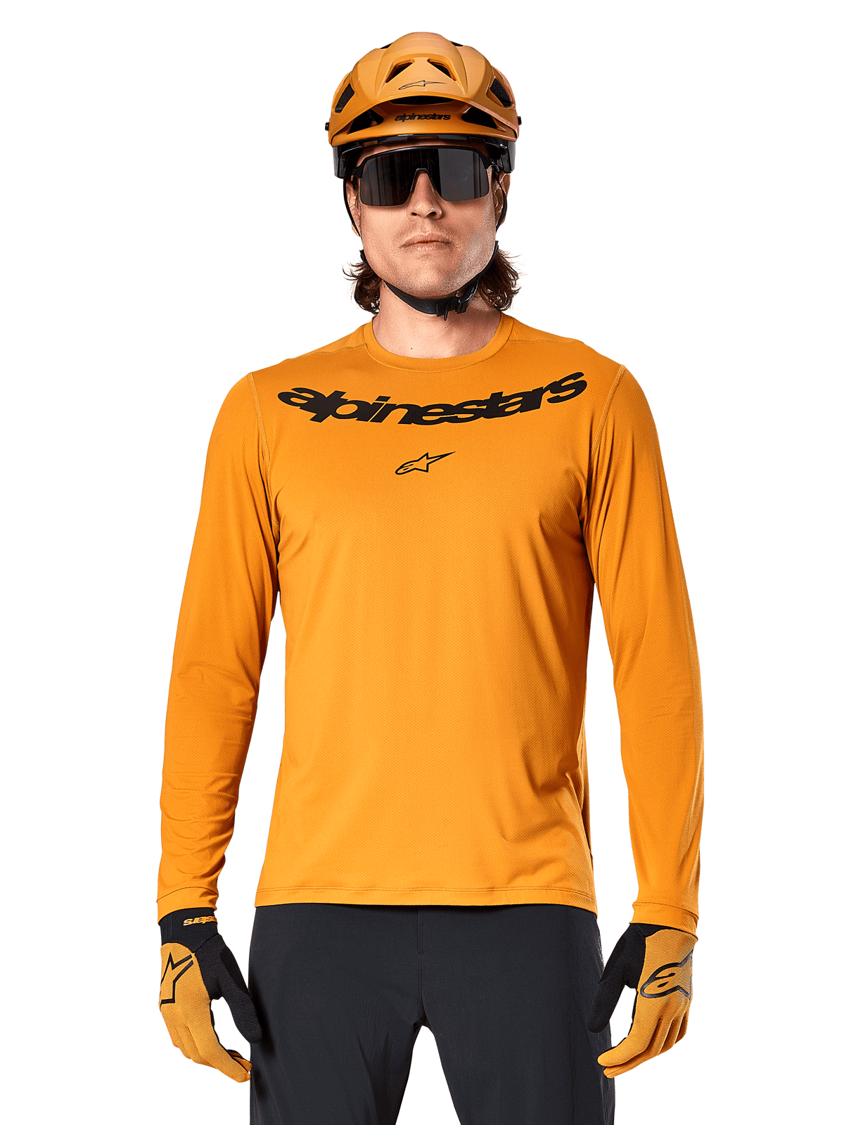 Alpinestars A-Dura Rocker langærmet trøje i Dark Gold, med et sort wordmark-logo på brystet, vist med en matchende guldhjelm og handsker til mountainbike-performance.