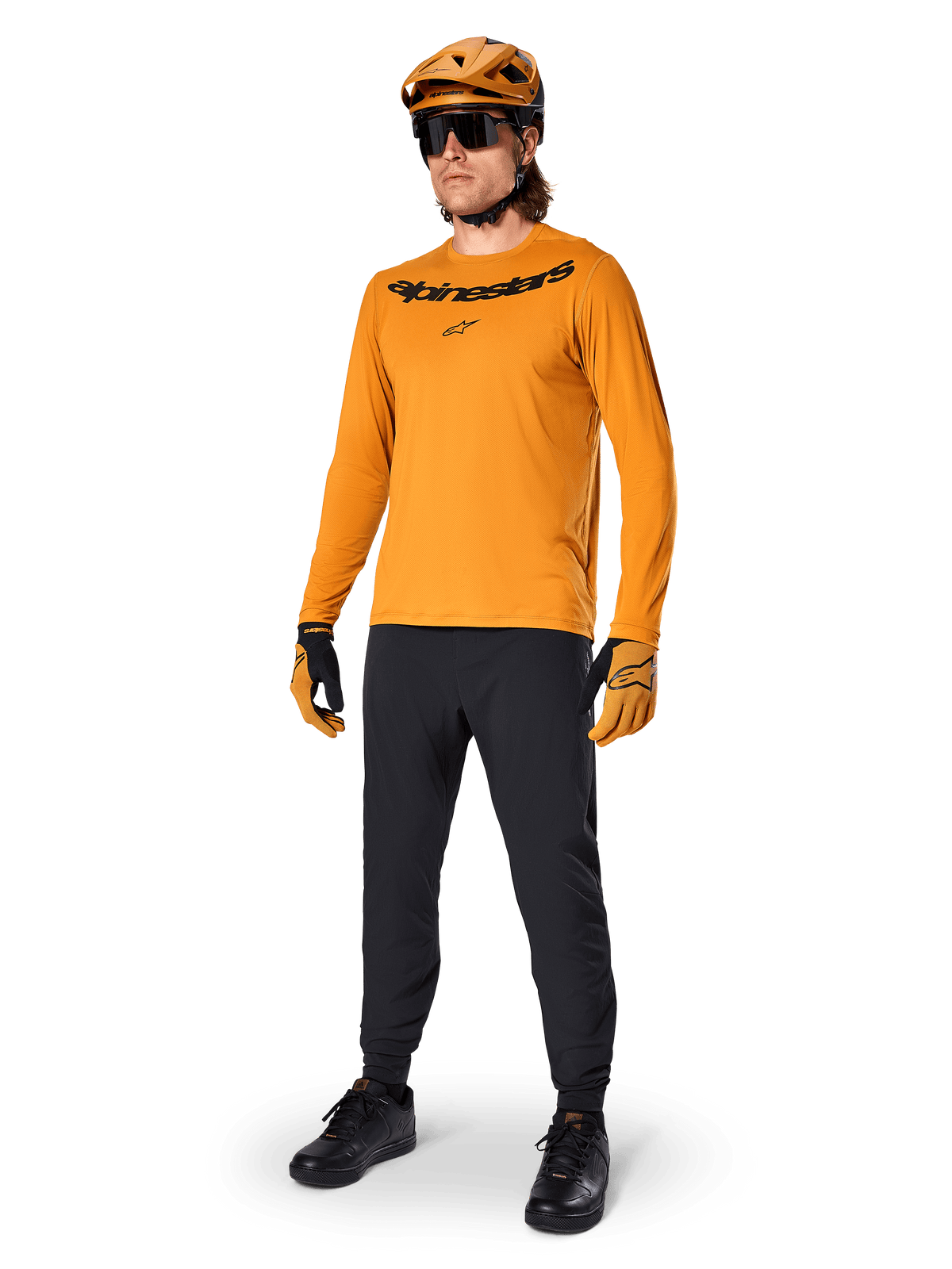 Alpinestars A-Dura Rocker langærmet trøje, mørk guld cykeltrøje, båret med matchende MTB-hjelm og sorte bukser, med sort wordmark-logo på brystet, koordineret performance-udstyr til off-road mountainbike