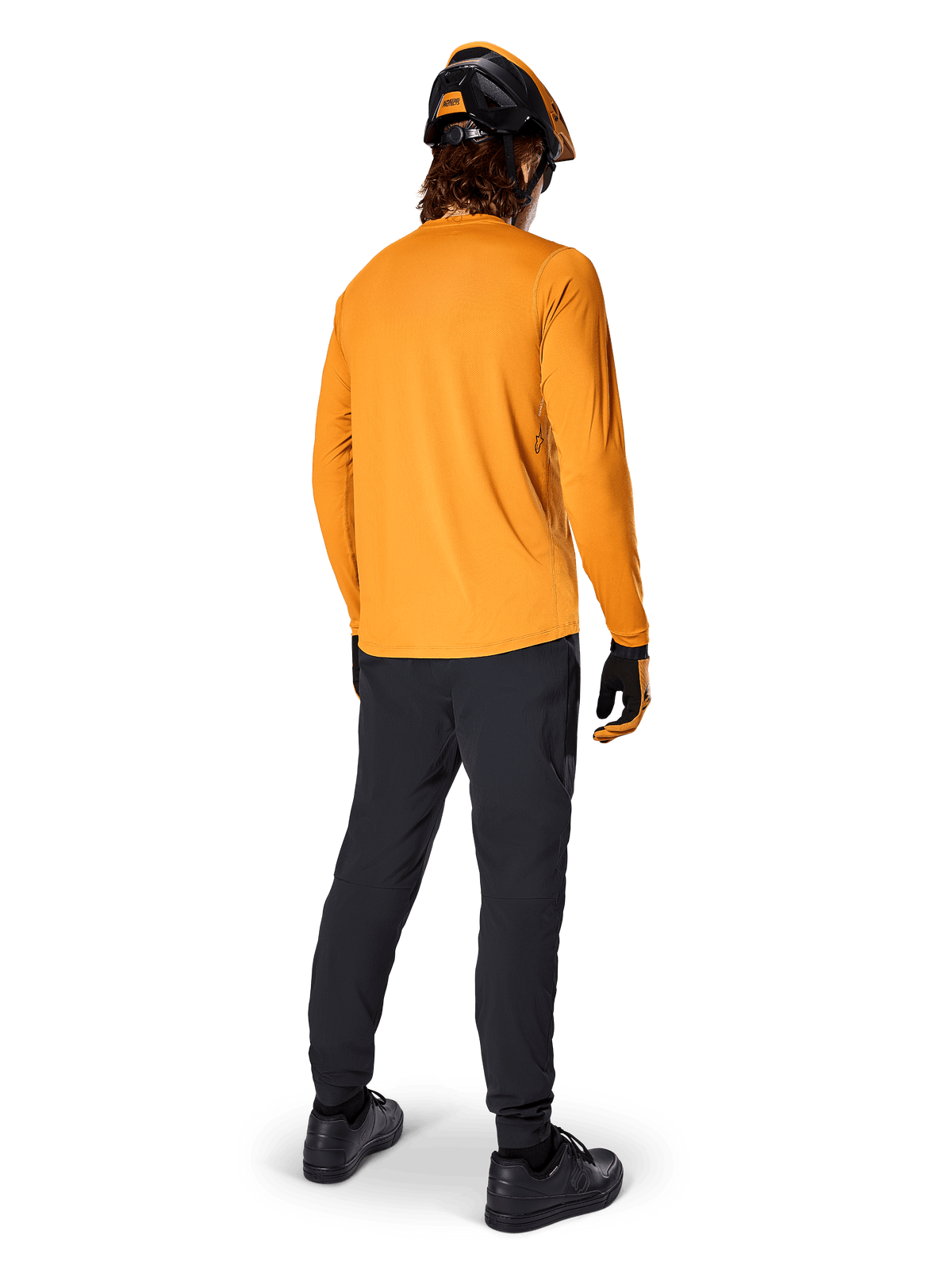 Mountainbikerytter set bagfra iført Alpinestars A-Dura Rocker langærmet trøje i Dark Gold, sorte bukser, orange og sort hjelm og sorte sko, koordineret performance MTB-udstyr til trailkørsel