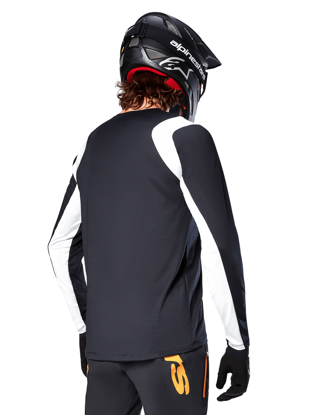MTB rider wearing Alpinestars A-Supra Oscar Long Sleeve Jersey, Black with white panels on the shoulders and sleeves, viewed from behind, black helmet and gloves, pants with orange accents, durable off-road cycling apparel