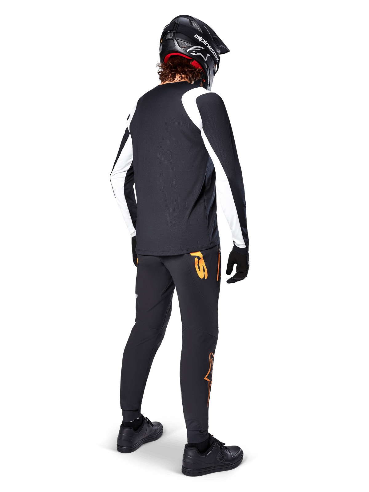 Alpinestars A-Supra Oscar Long Sleeve Jersey, Black with white panels on sleeves, worn by an MTB rider from the back with a black full-face helmet and black pants featuring orange logos, cycling apparel for off-road gravity riding