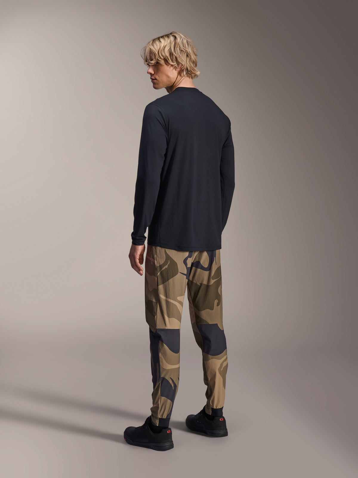 Alpinestars A-Dura Astar langærmet trøje, sort, rygvisning på en model, kombineret med camouflagebukser, afslappet MTB-performance-udstyr med længere drop hale og almindelig pasform
