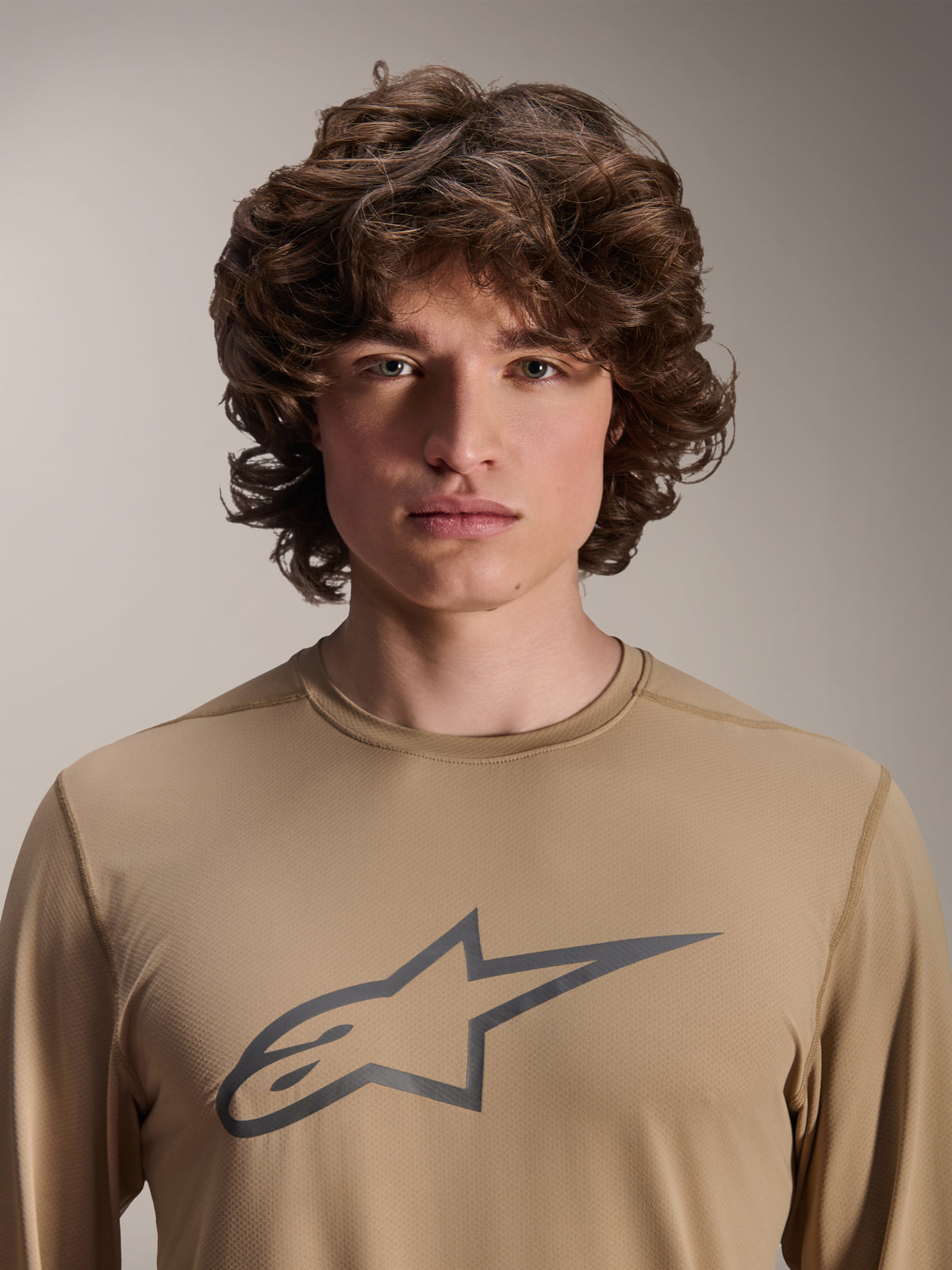 Alpinestars A-Dura Astar langærmet trøje, lysebrun, båret af mandlig model, med et stort Astars-logo på brystet, jacquard-stoftekstur, afslappet mountainbike-tøj