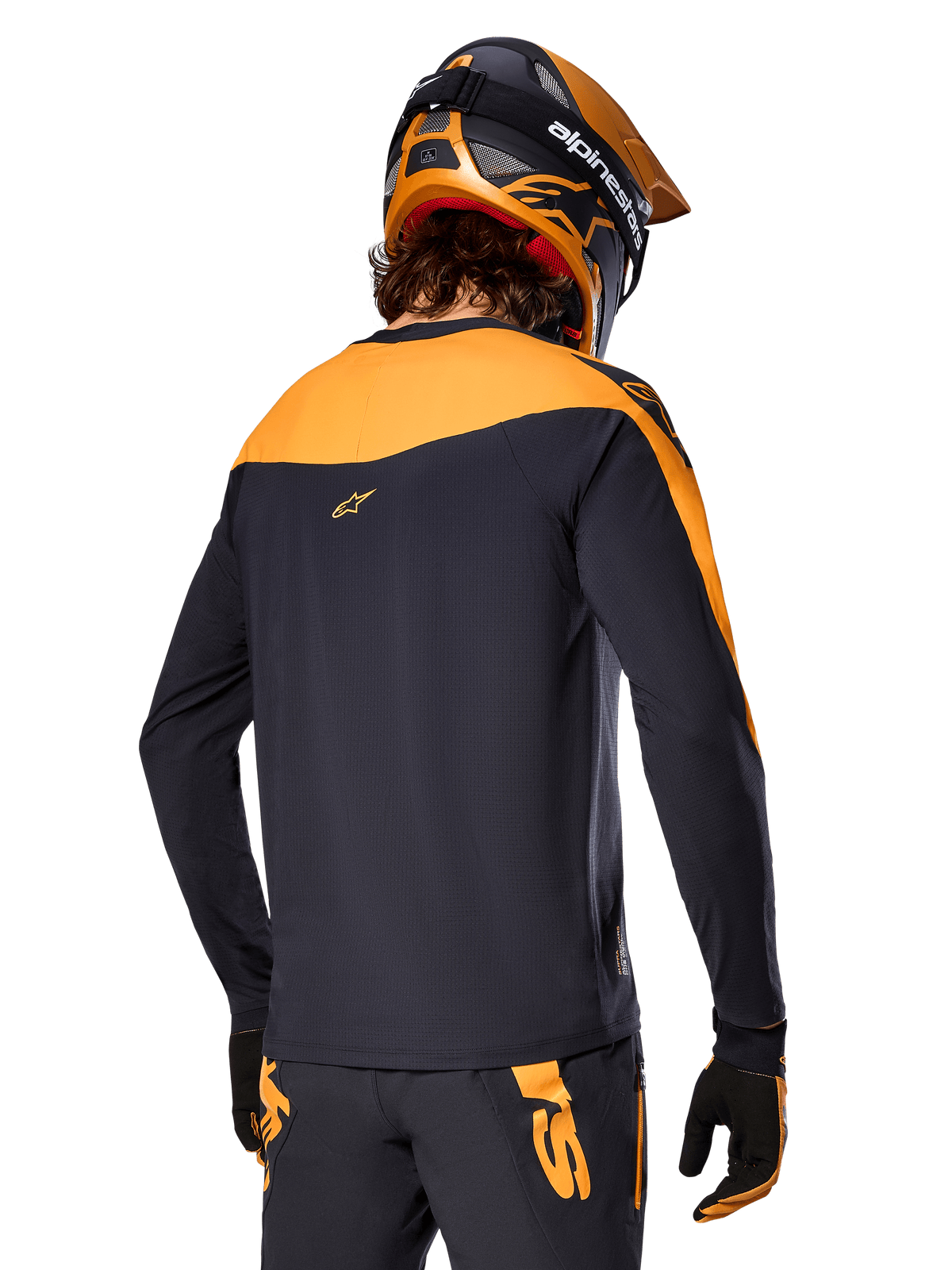 Alpinestars A-Supra Race Jersey - Langærmet, sort og orange, set bagfra af rytter iført matchende hjelm og mountainbike-bukser, performance-pasform med mikroperforeret tekstur, professionelt MTB-racerudstyr