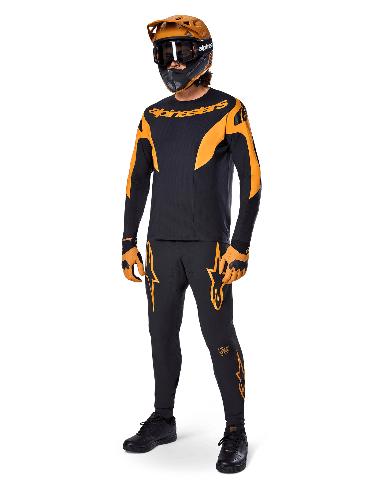 MTB-rytter iført komplet racerudstyr, sort A-Supra Race-trøje med orange detaljer, matchende sorte bukser med orange Alpinestars-logoer, orange og sort full-face-hjelm med goggles, orange og sorte handsker, koordineret outfit til mountainbike-løb