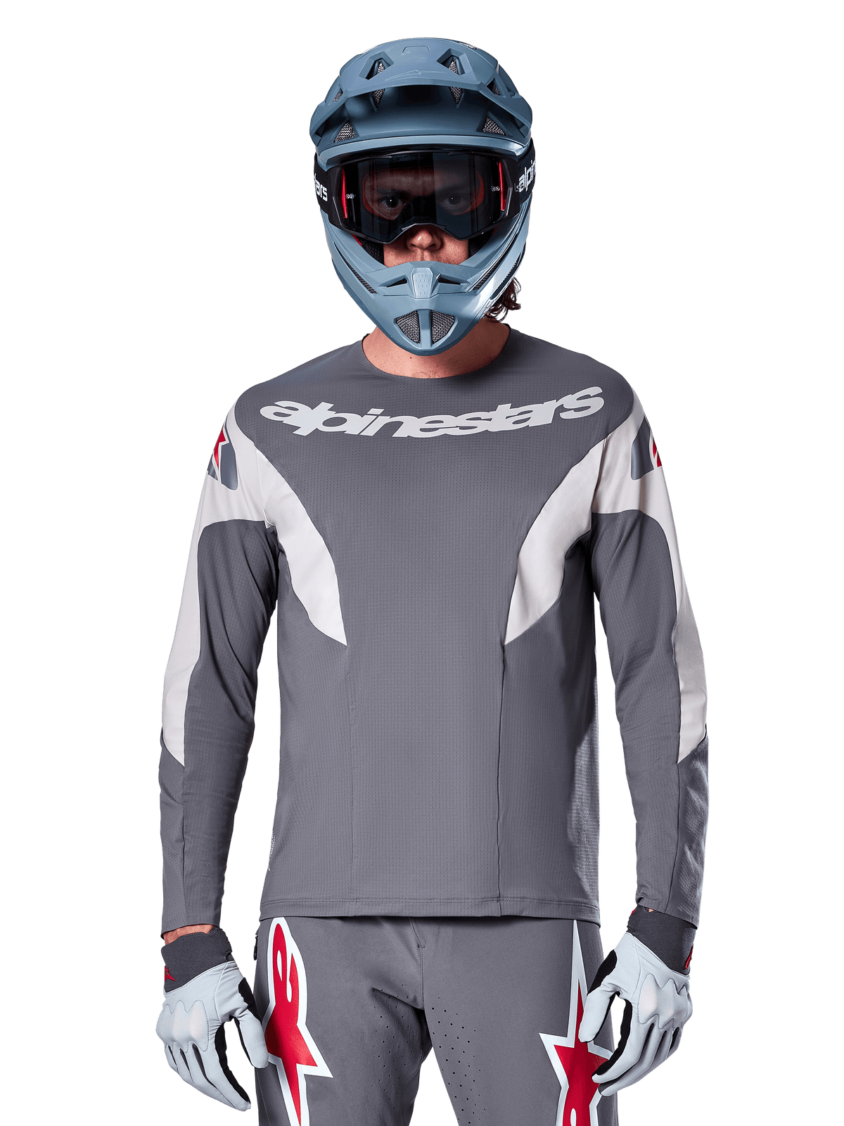 MTB-rytter iført Alpinestars A-Supra Race Jersey - Long Sleeve i Dark Gray, langærmet cykeltrøje med hvidt Alpinestars-logo, kombineret med blågrå full-face hjelm, goggles og grå racinghandsker, komplet mountainbike-racerudstyr til off-road performance