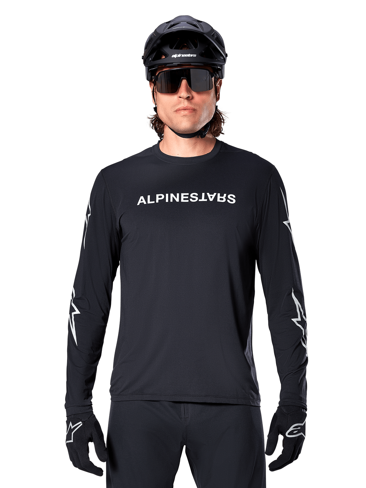 Alpinestars A-Dura Switch langærmet trøje, sort MTB-trøje, hvidt Alpinestars-ordmærke på brystet og stjernegrafik på ærmerne, båret med sort mountainbikehjelm og performance-solbriller, teknisk trail-cykeltøj
